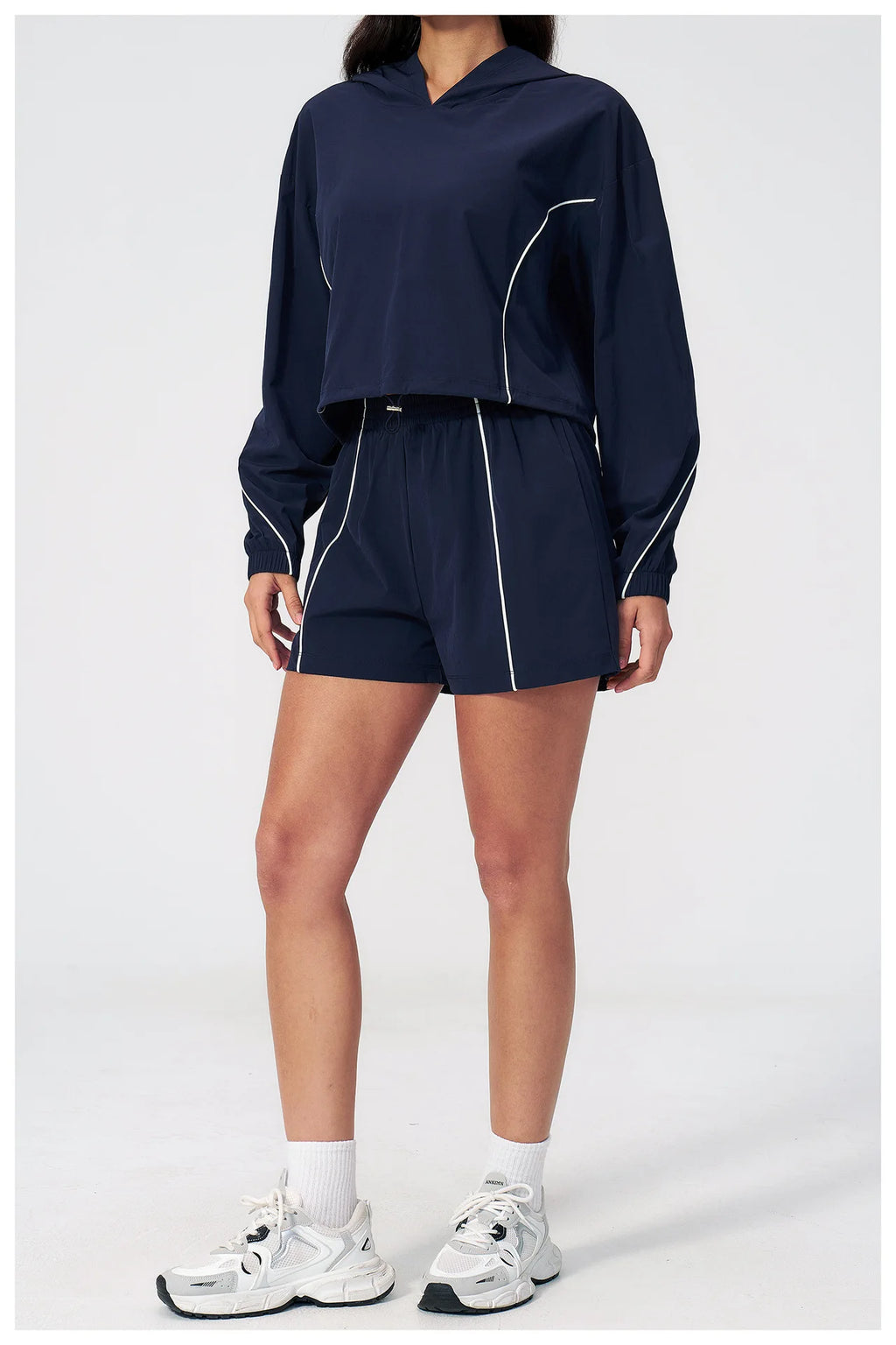 Women’s hooded windbreaker set in navy, cropped top with matching shorts and white piping