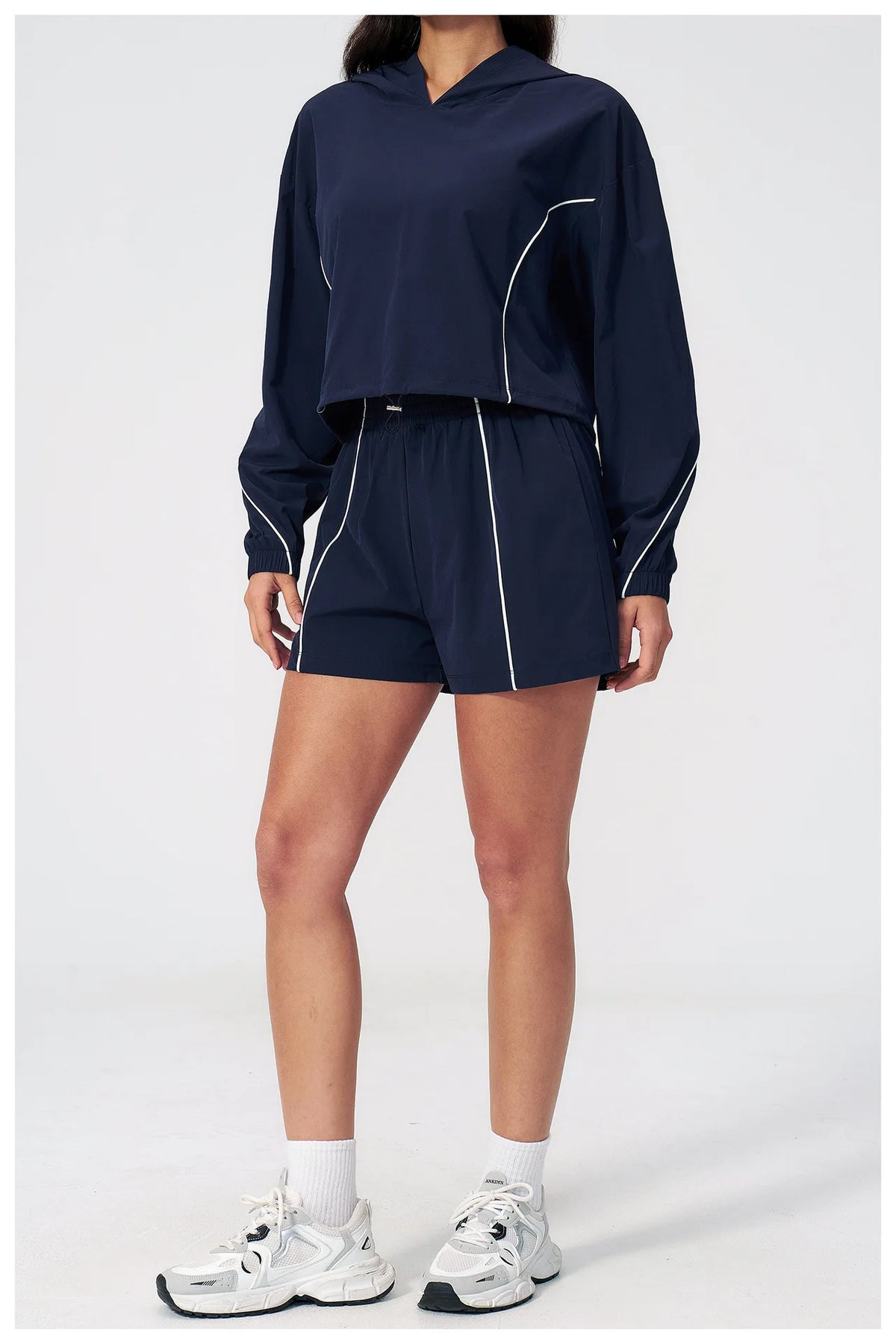 Women’s hooded windbreaker set in navy, cropped top with matching shorts and white piping