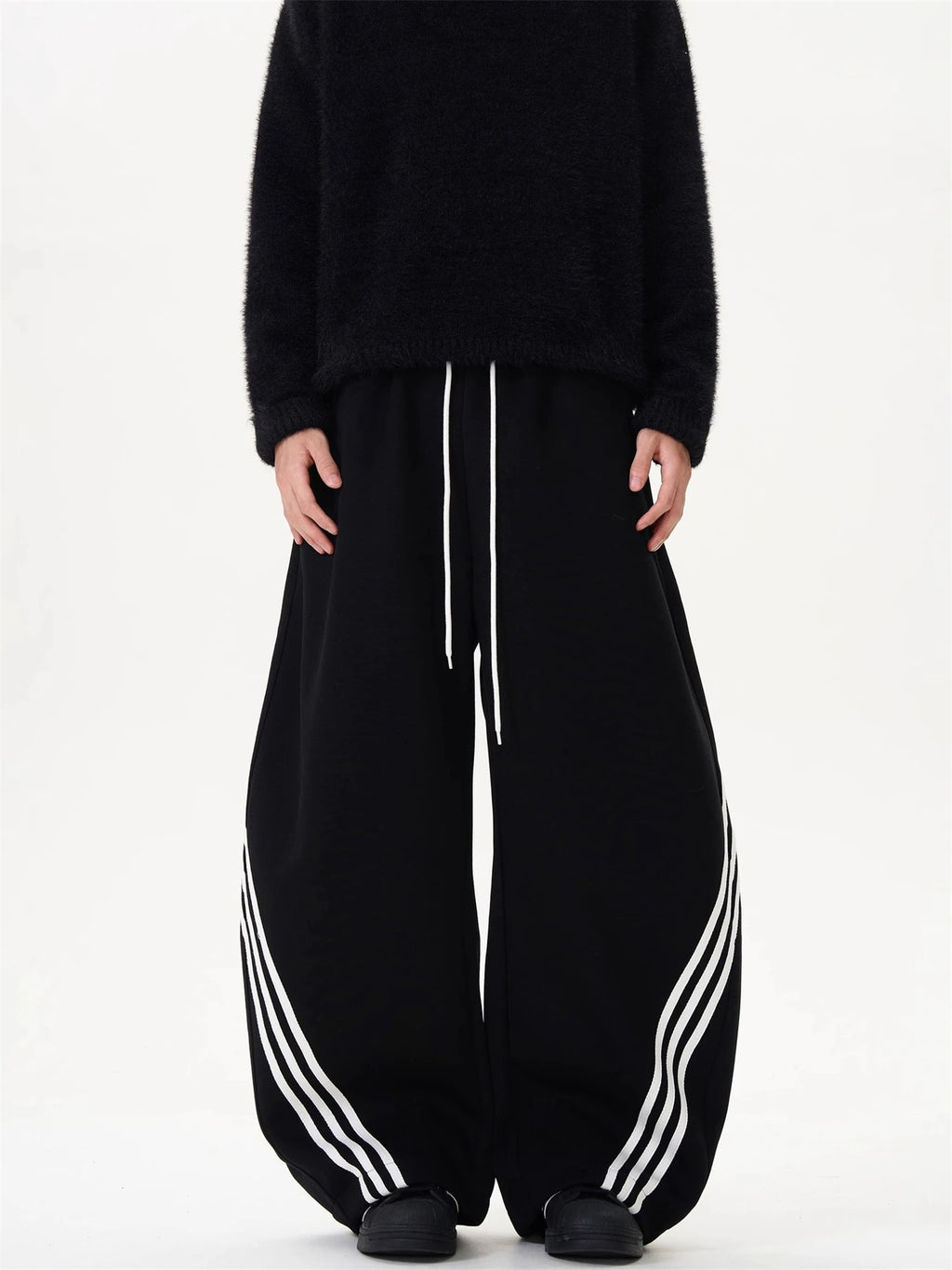 Wide-leg sweatpants in black with white side stripes and center drawstring waist.