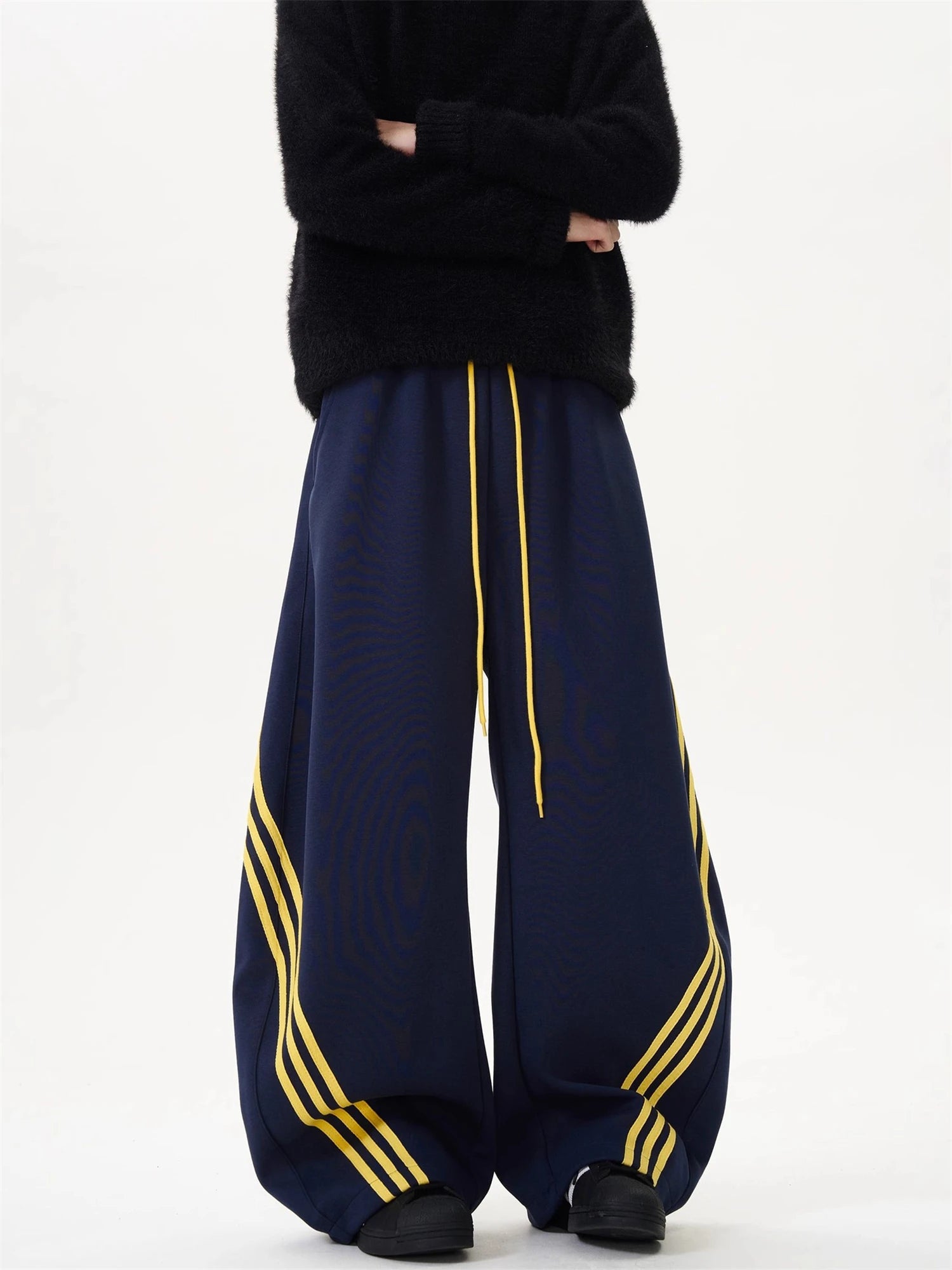 Oversized wide-leg sweatpants in dark navy with yellow side stripes and center drawstring.