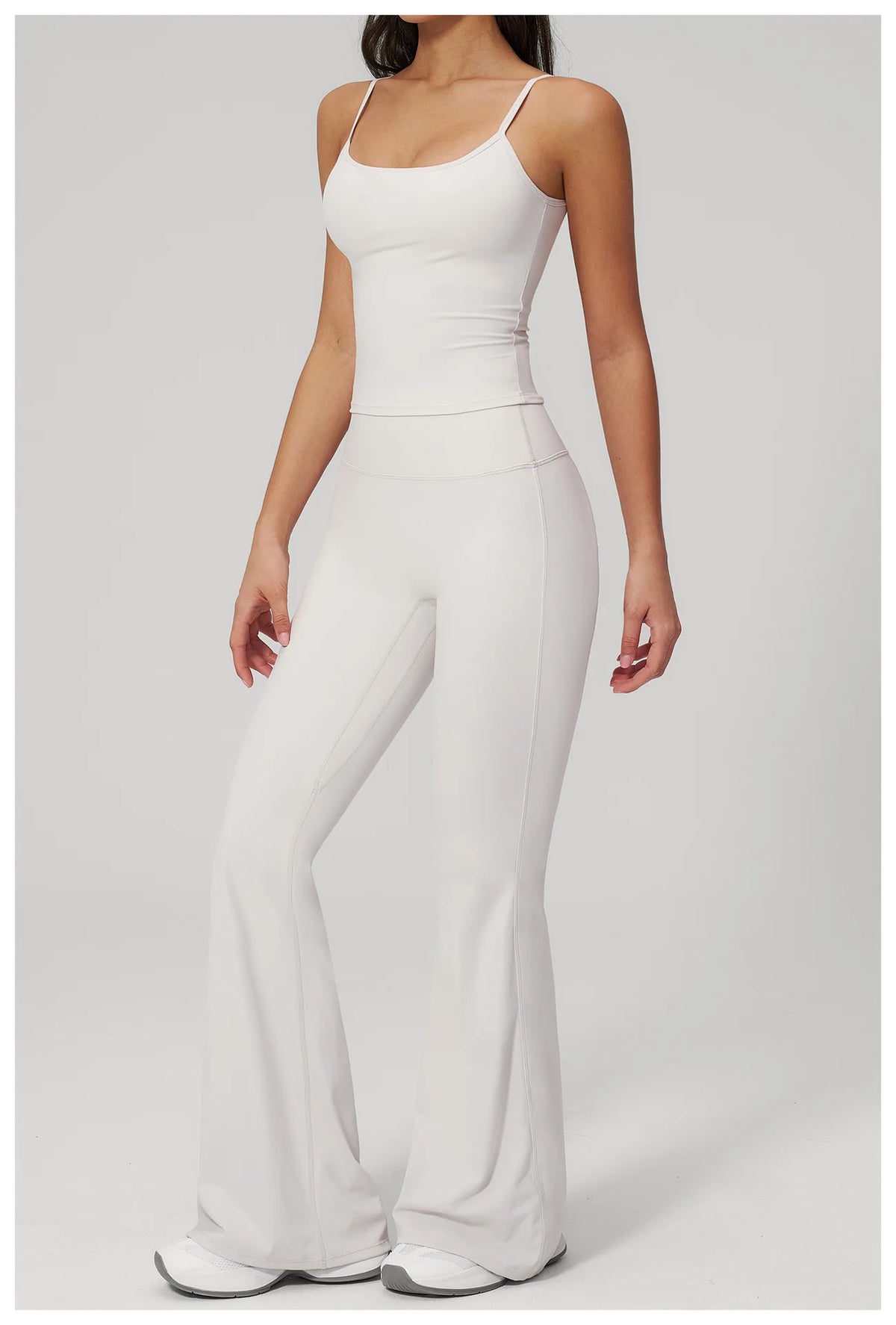 White sports set: wide-strap tank bra and flare leggings, standing side view