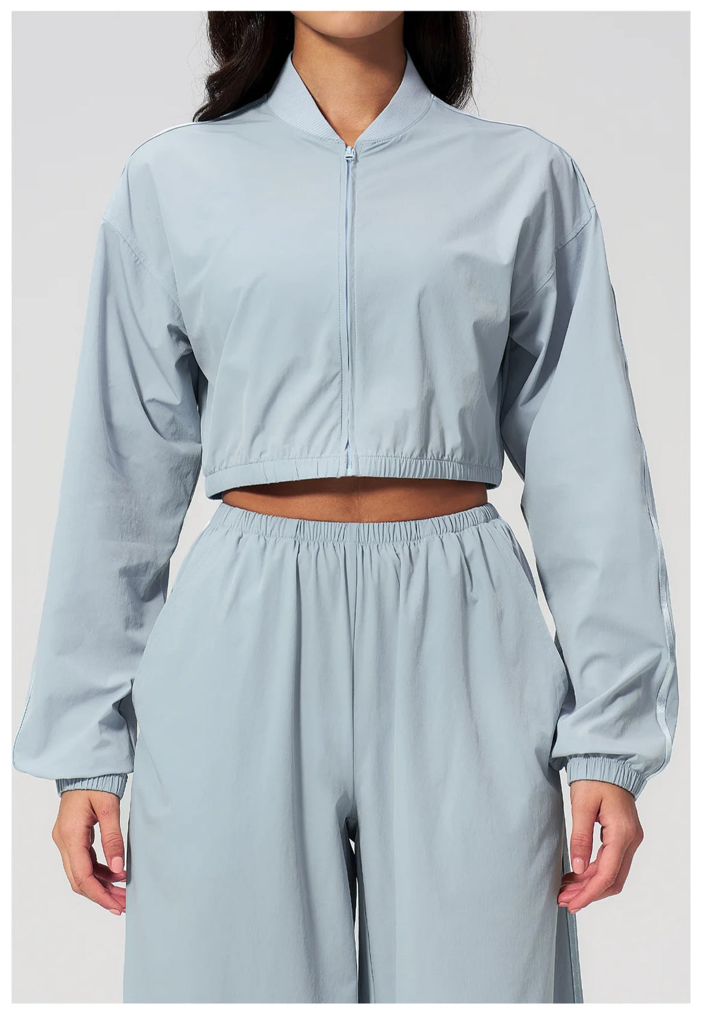 Women’s cropped zip-up jacket in sky blue with long sleeves and elastic waist pants.