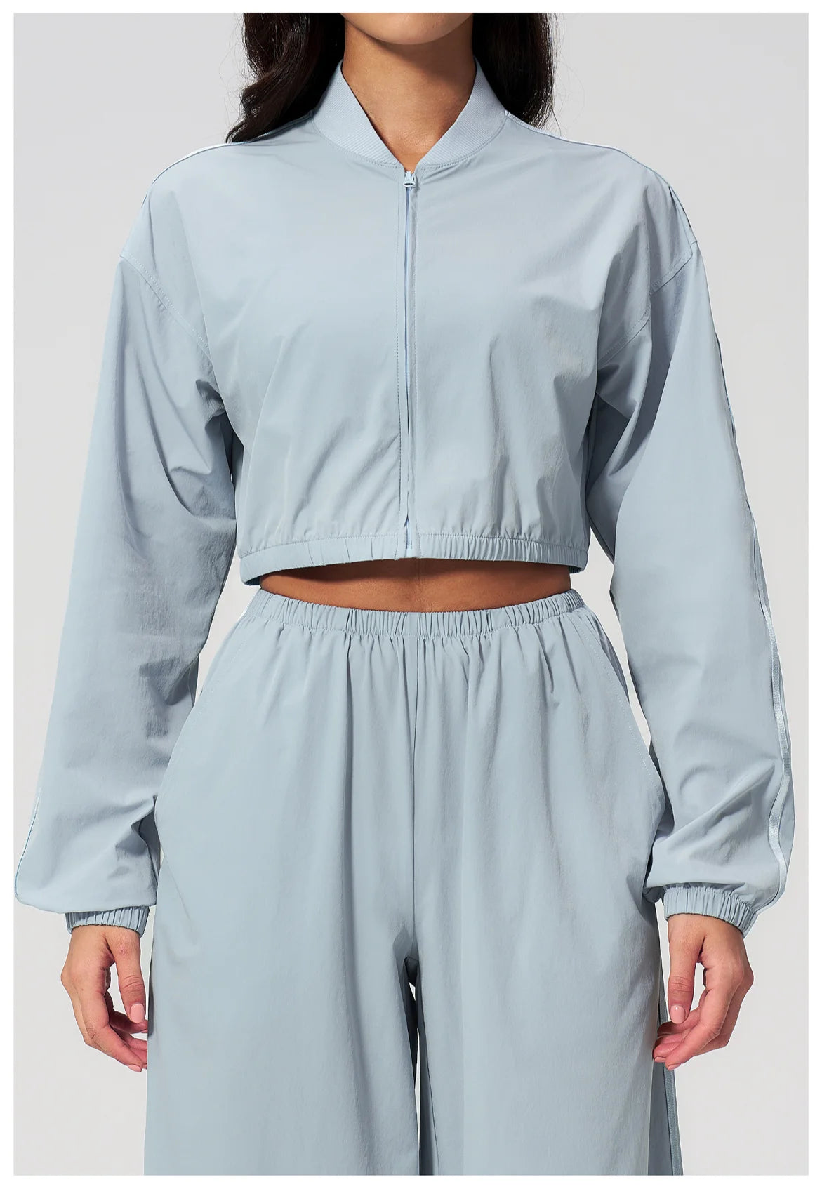 Women’s cropped zip-up jacket in sky blue with long sleeves and elastic waist pants.