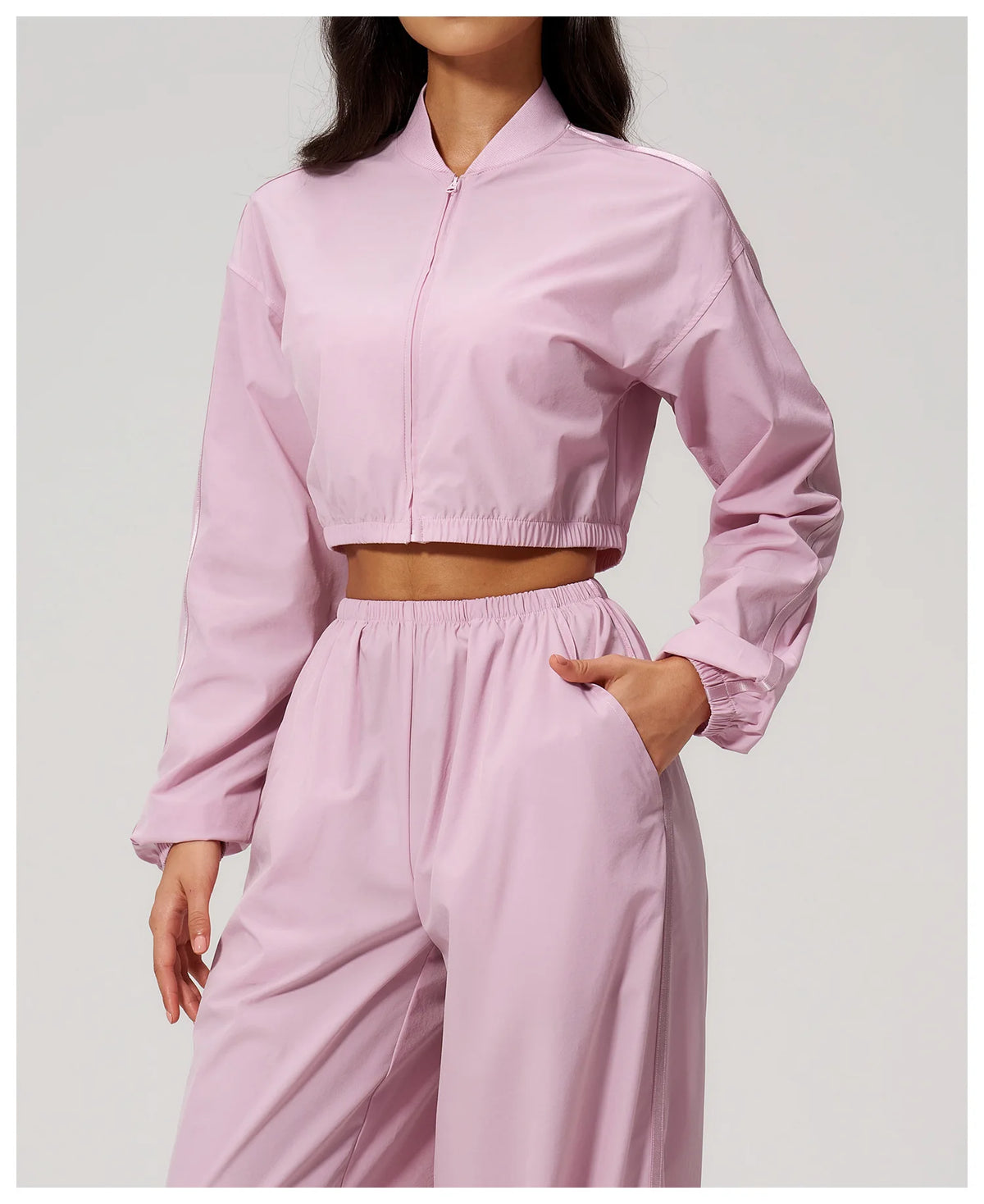 Women’s light pink zip-up cropped jacket with long sleeves and front hand pocket seam.