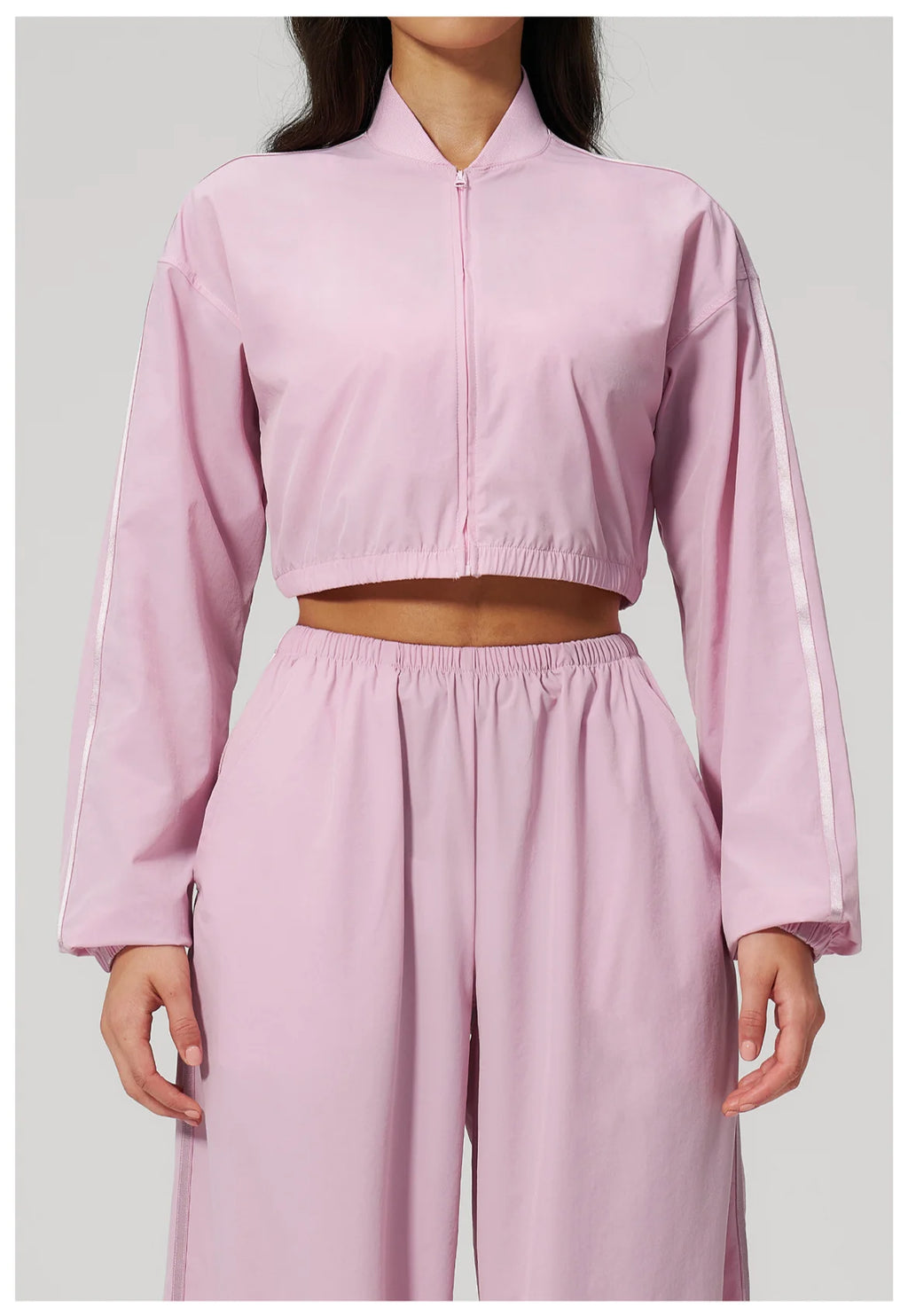 Women’s cropped zip-up jacket in light pink with long sleeves and matching elastic waist.