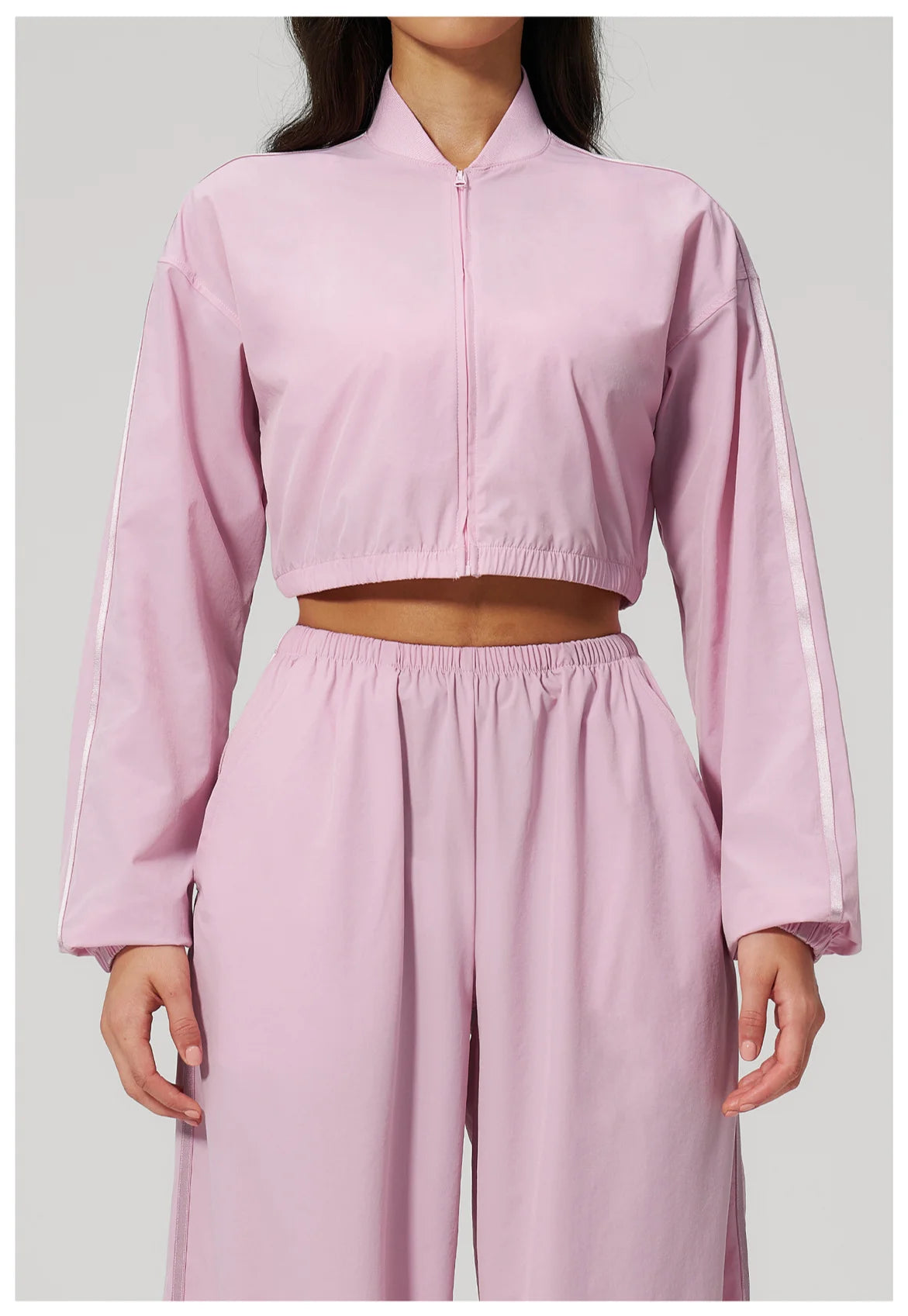 Women’s cropped zip-up jacket in light pink with long sleeves and matching elastic waist.