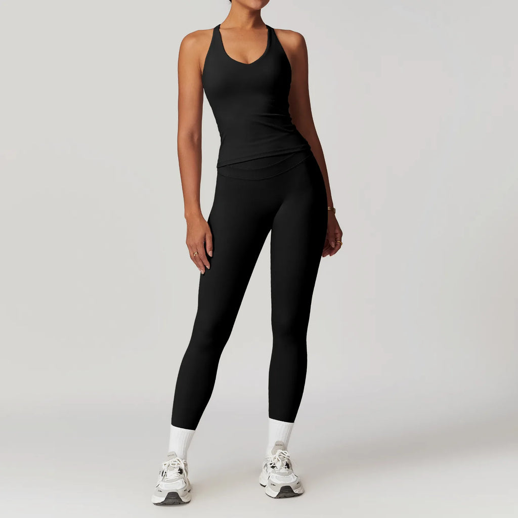 Black fitness tank top and biker shorts set by Xooie Fit modeled by woman with white sneakers