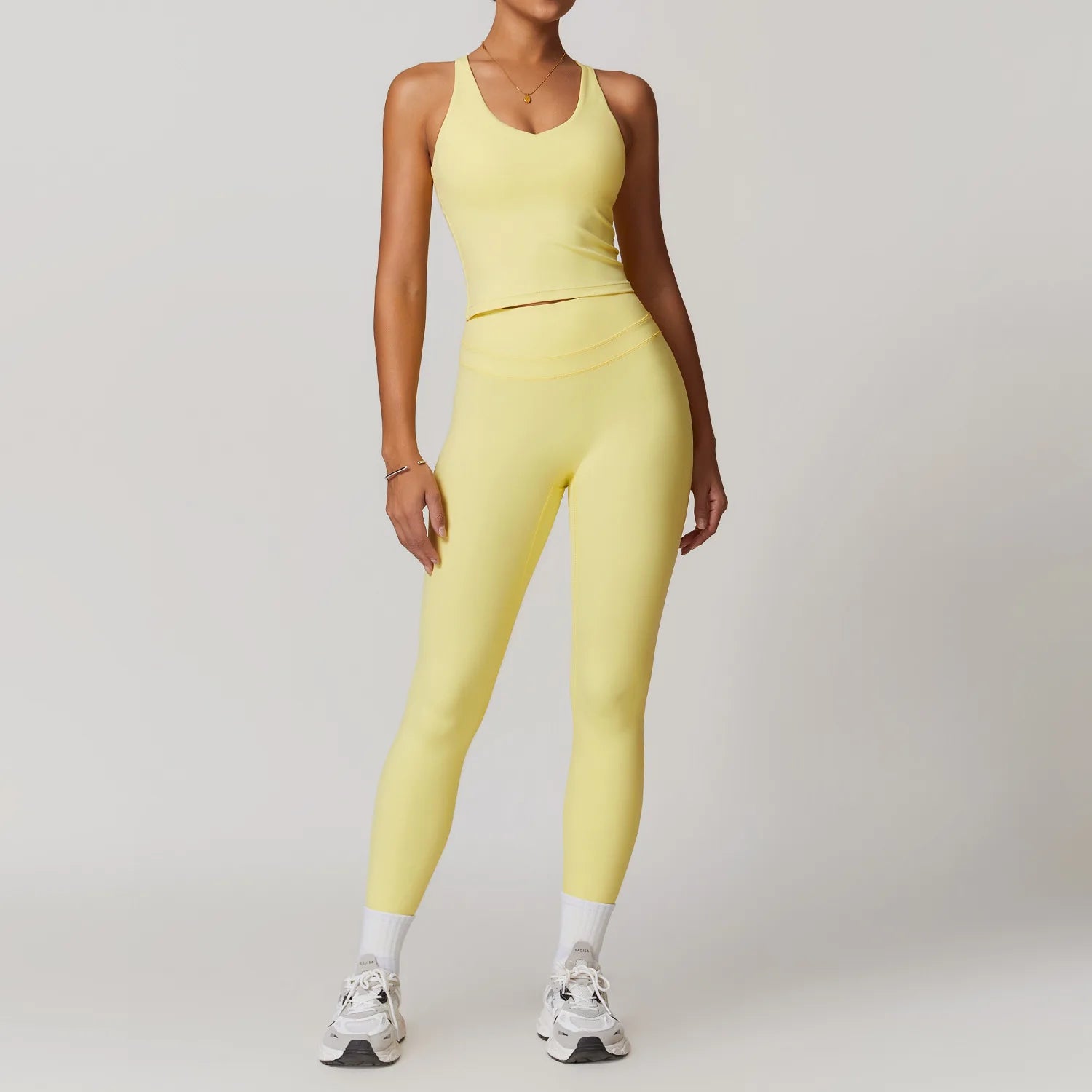 Xooie Fit yellow fitness tank top and biker shorts set worn by model with white sneakers2