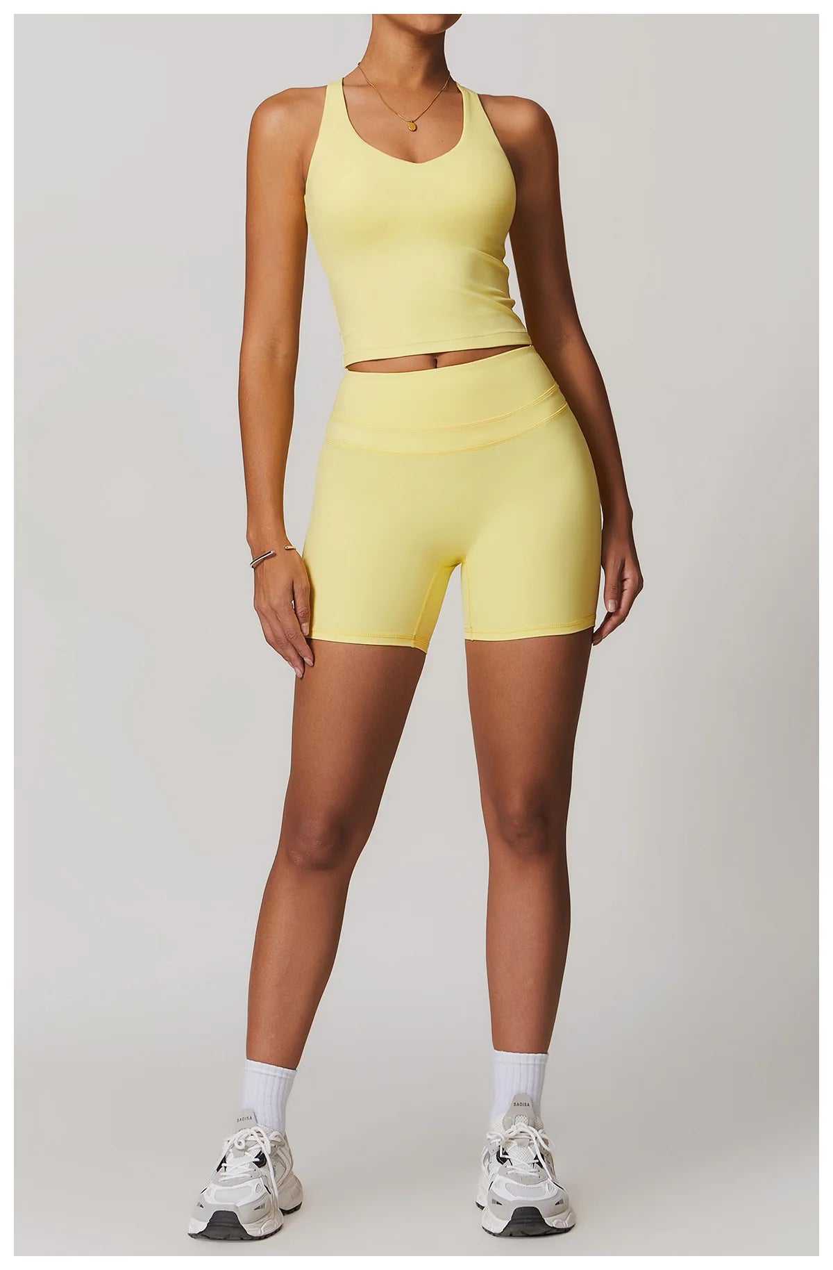 Xooie Fit yellow fitness tank top and biker shorts set worn with white sneakers and socks