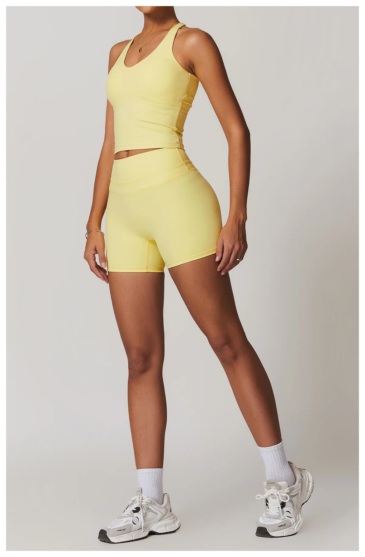 Xooie Fit yellow fitness tank top and biker shorts set worn by model with white sneakers