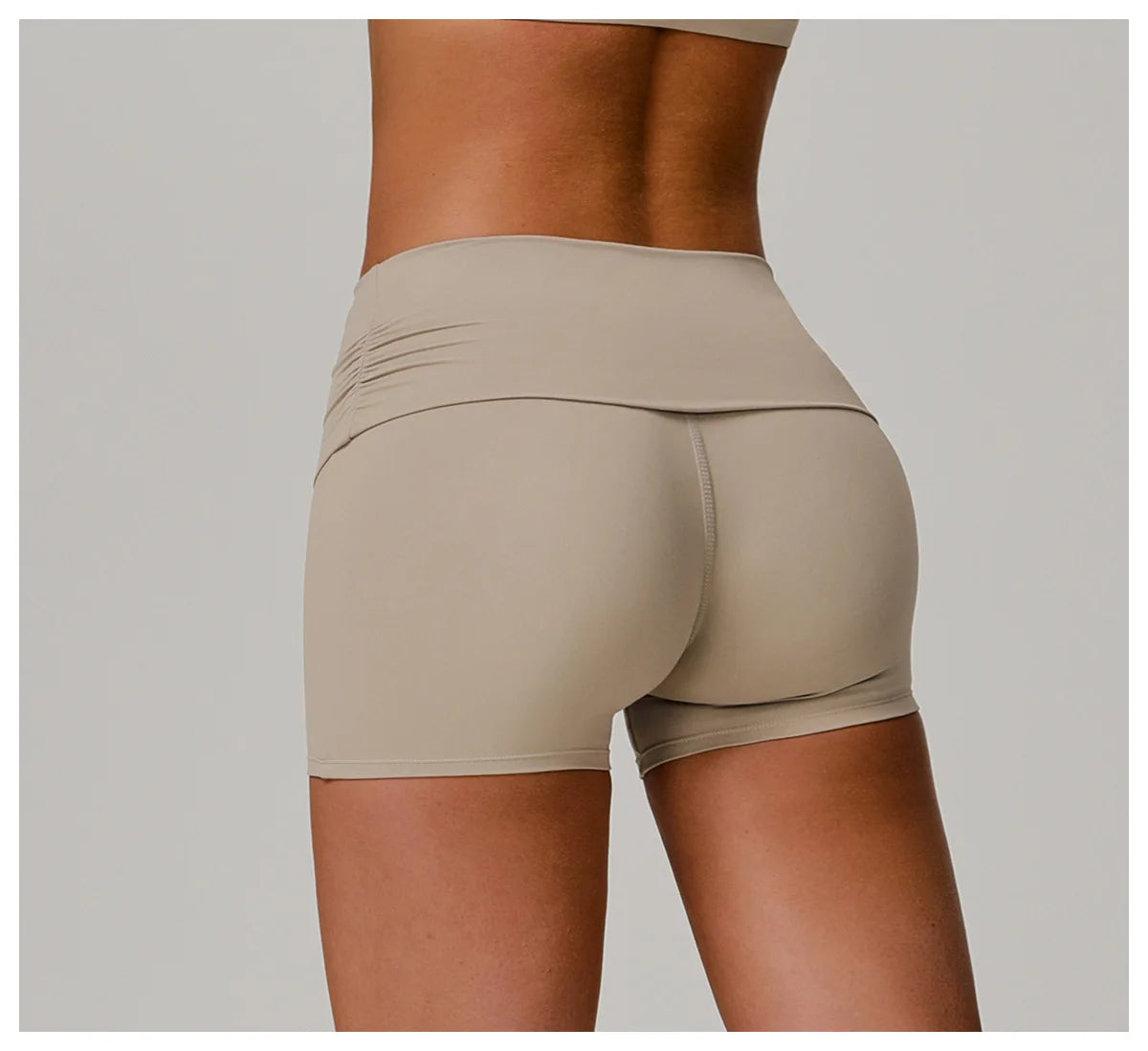 Xooie Fit beige foldable waistband yoga shorts shown from the back on a toned model
