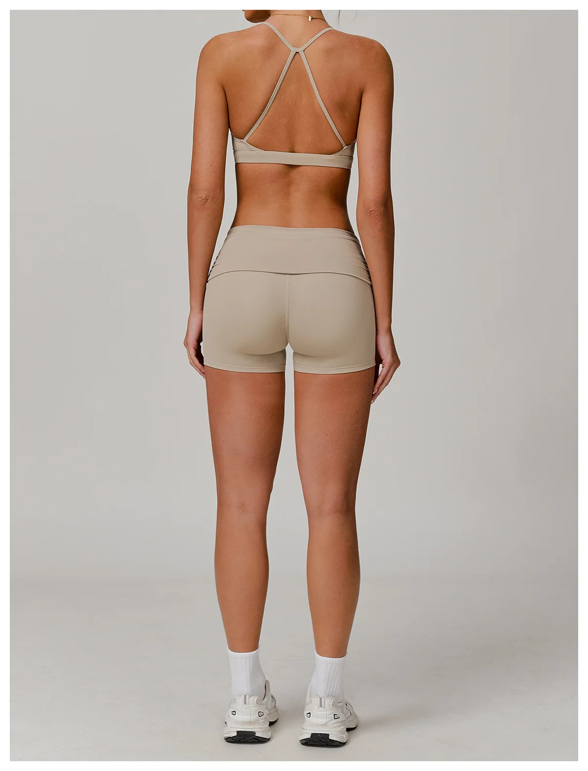 Xooie Fit foldable waistband yoga shorts in beige worn by woman with white sneakers and sports bra