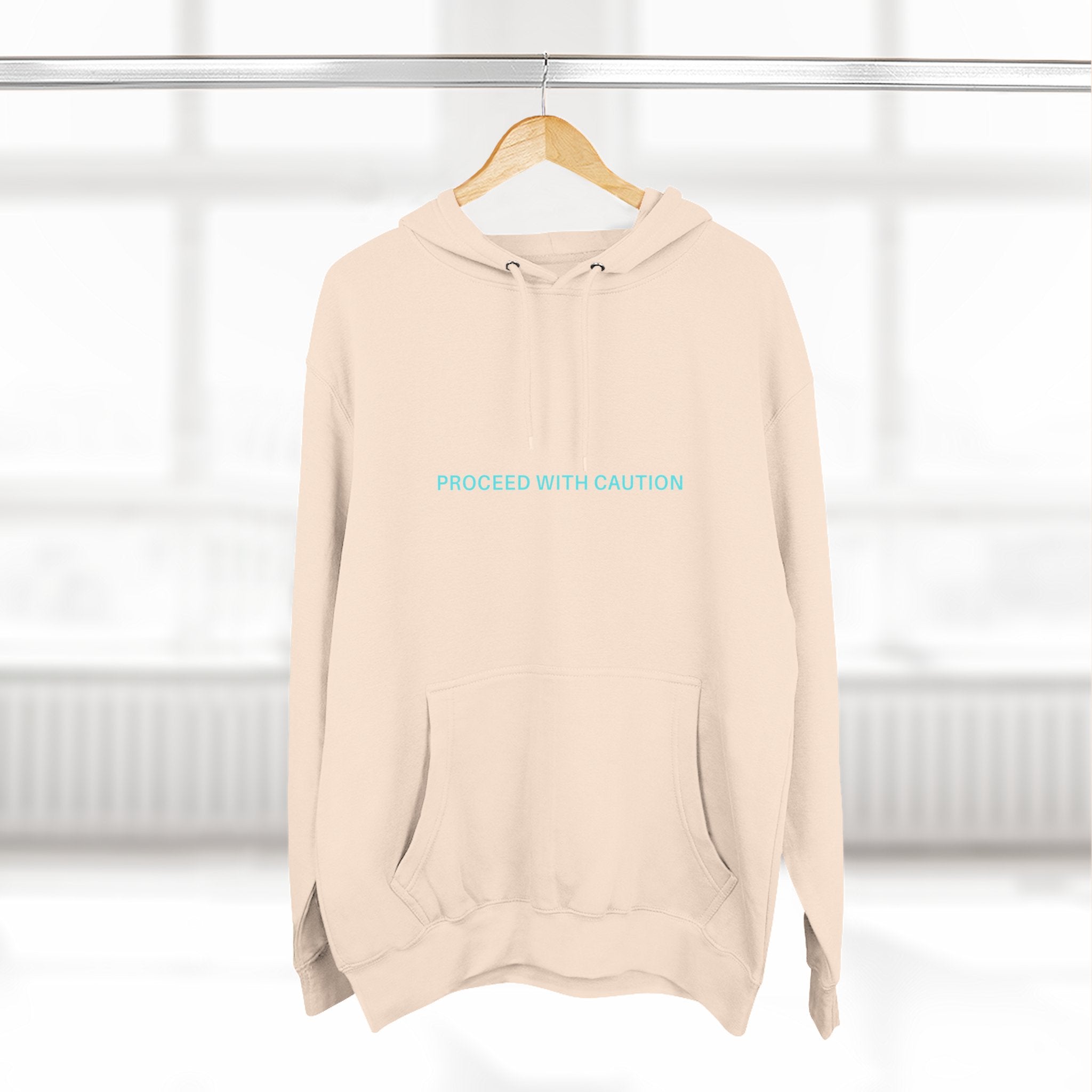 Off-white fleece hoodie with hood and kangaroo pocket, chest “PROCEED WITH CAUTION”