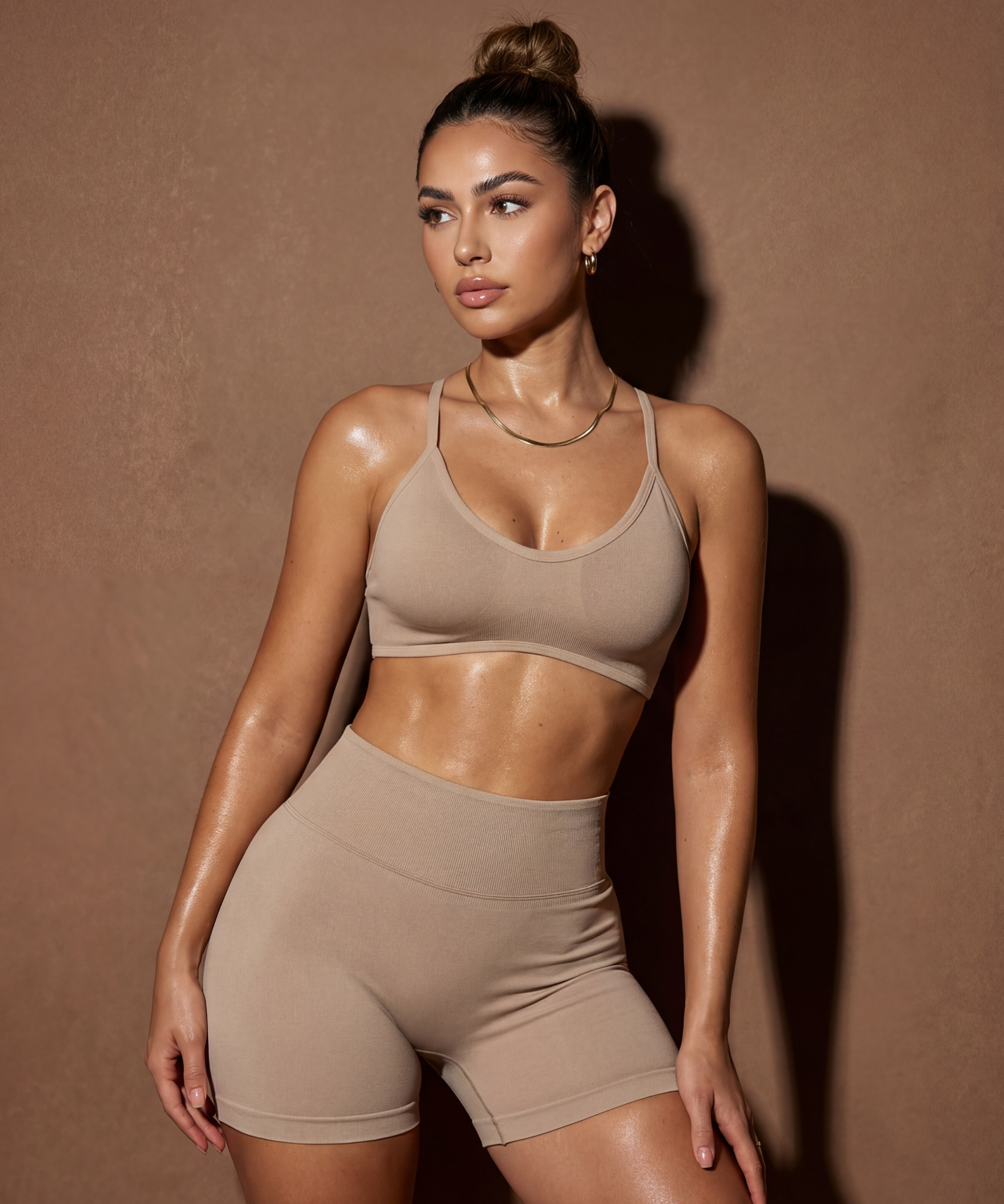 Woman wearing a beige sports bra and shorts against a brown background