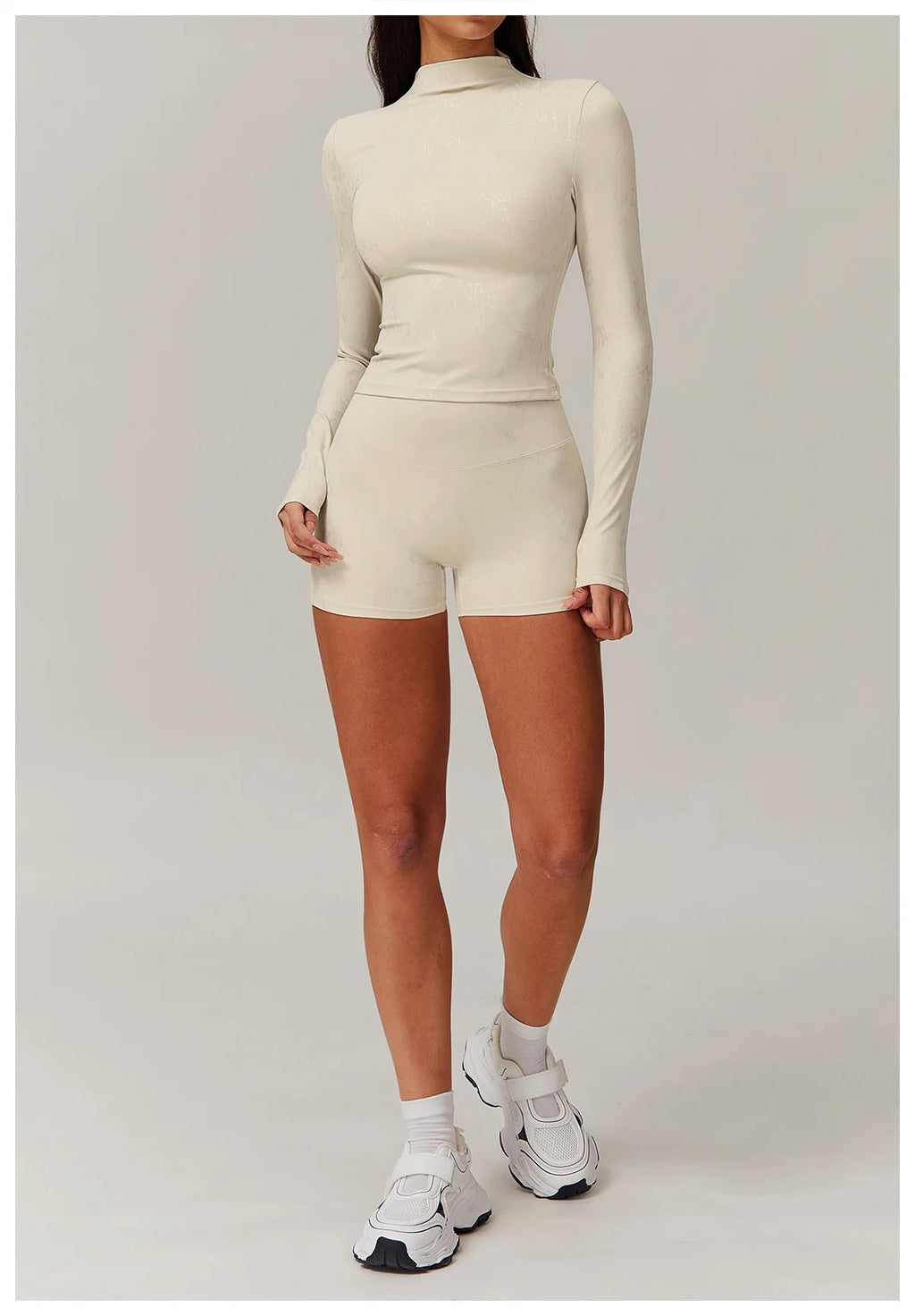 Light ivory textured long-sleeve fitted top and matching high-waist shorts set, full body