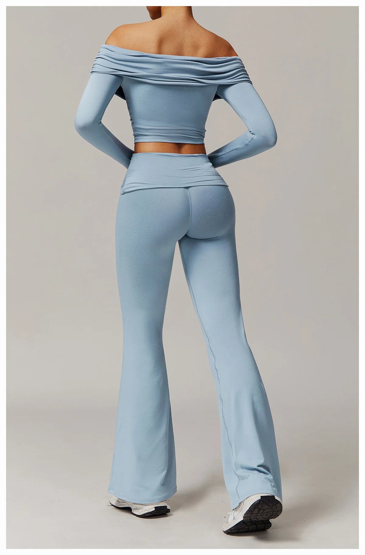 Woman wearing a light blue off the shoulder flare pant yoga set from Xooie Fit, shown from the back