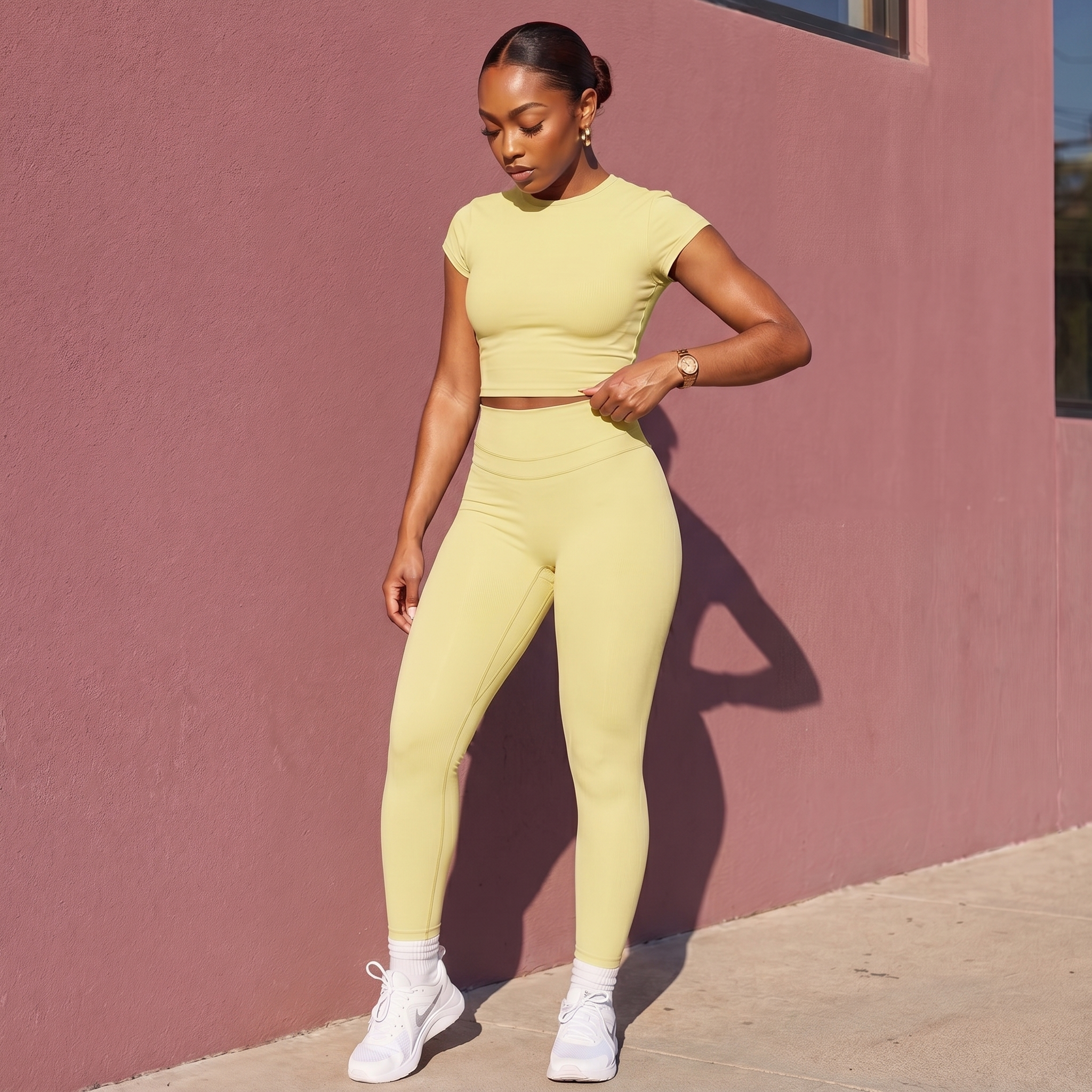Woman in a yellow outfit standing against a pink wall