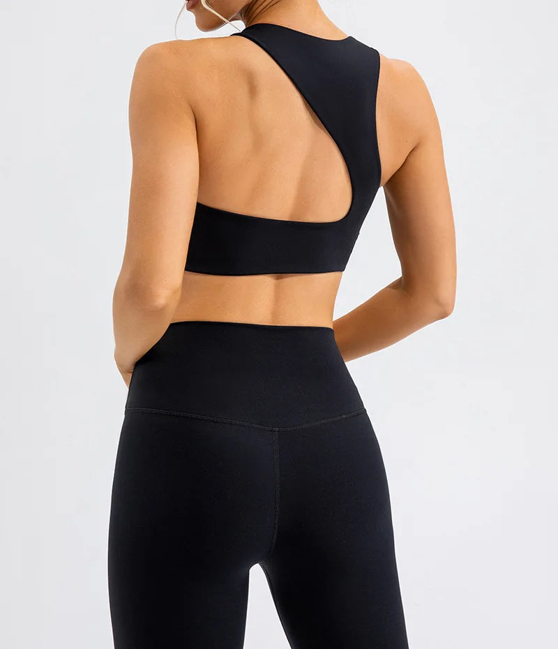 Xooie Fit black unique open-back bralette with asymmetrical design on woman wearing black leggings