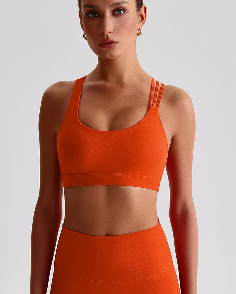 Unique strappy sports bra for women in vibrant orange, offering stylish support for workouts