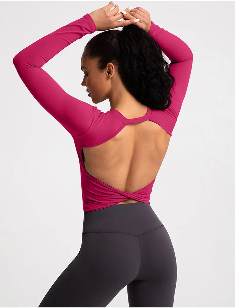 Xooie Fit backless long sleeve workout crop top in pink, showcasing an open back design