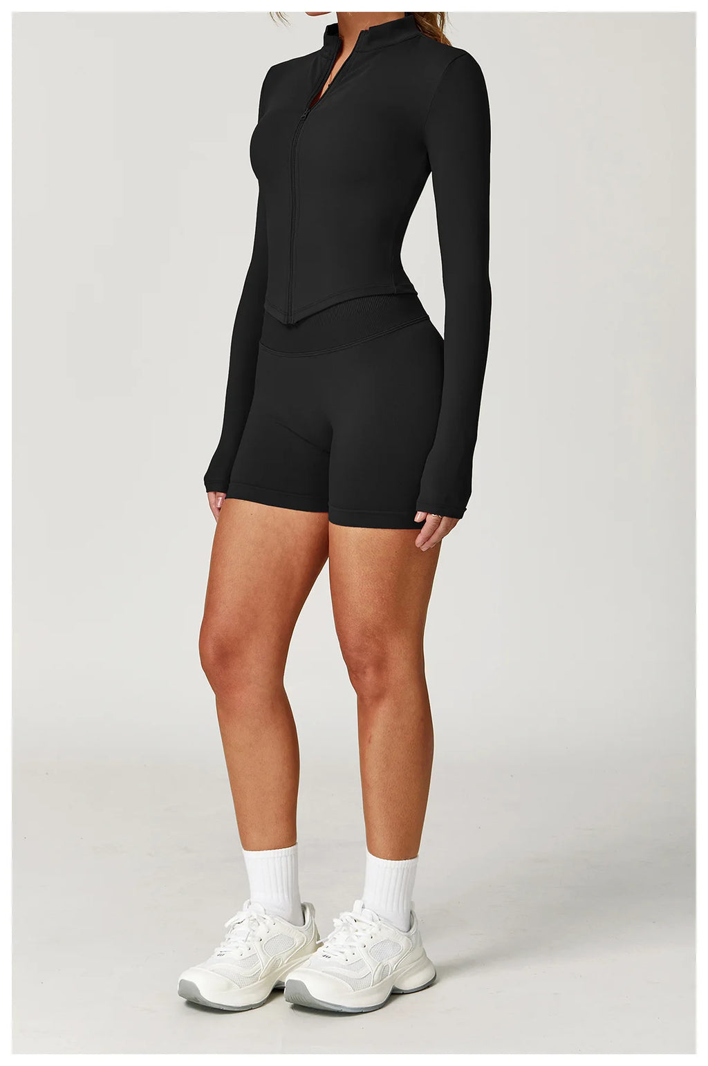 Black fitted zip jacket and matching active shorts set, long sleeves, side view