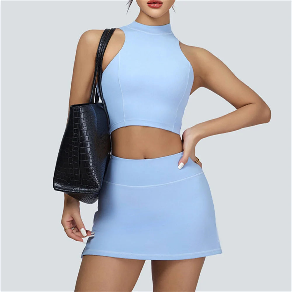 Xooie Fit light blue vest crop top and skort set worn by model with black handbag