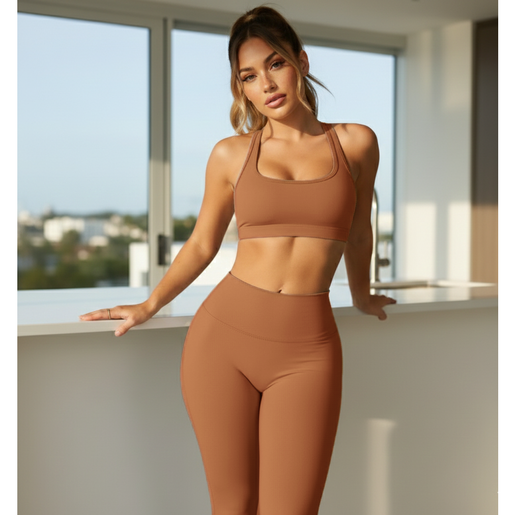 Woman in brown sports bra and leggings standing by a window with a cityscape view.