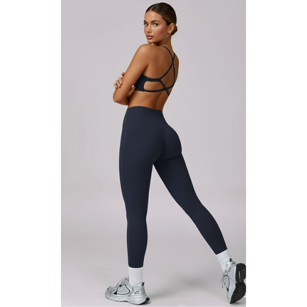 Woman wearing a black sports bra and navy leggings on a light gray background