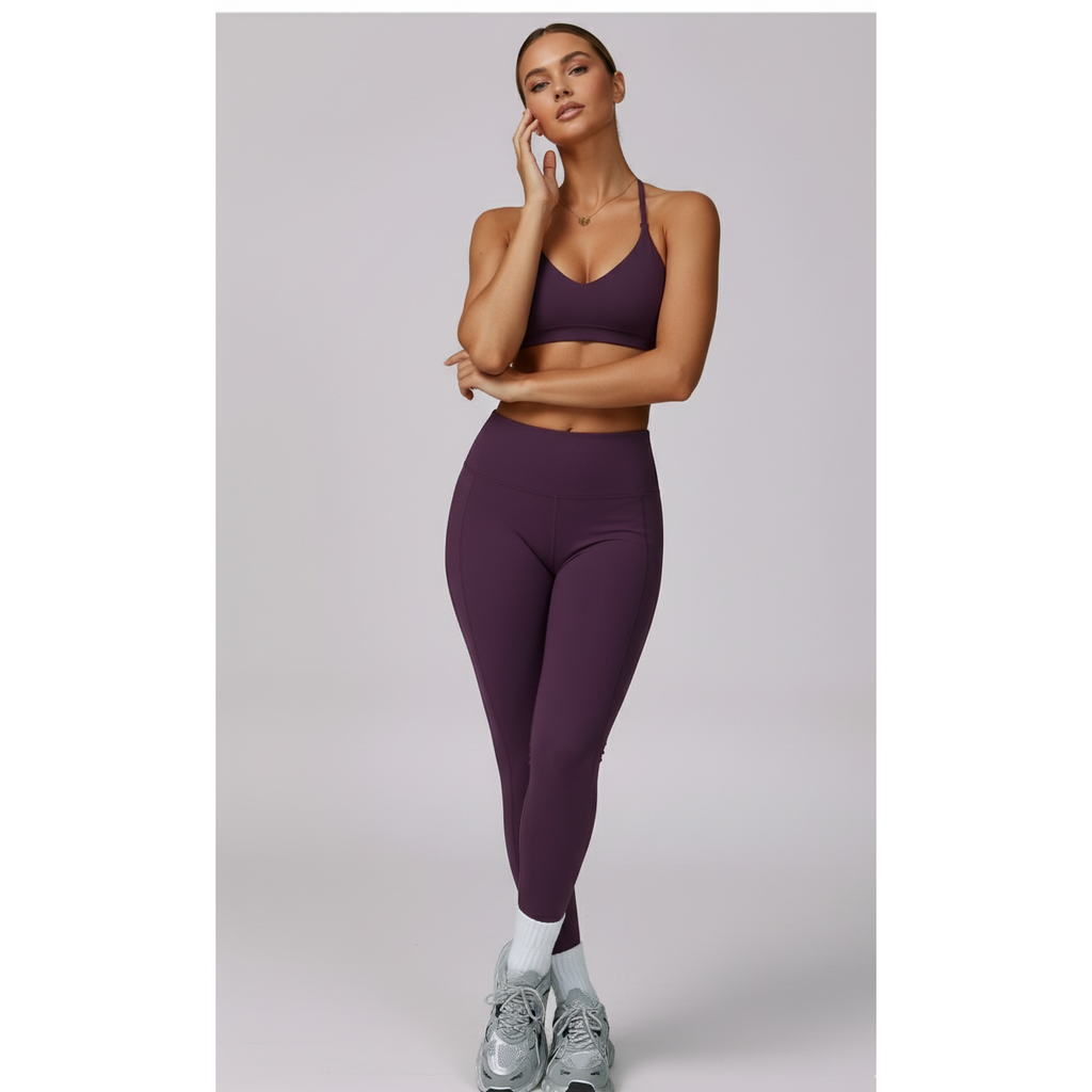 Woman wearing a purple sports bra and leggings set on a light gray background