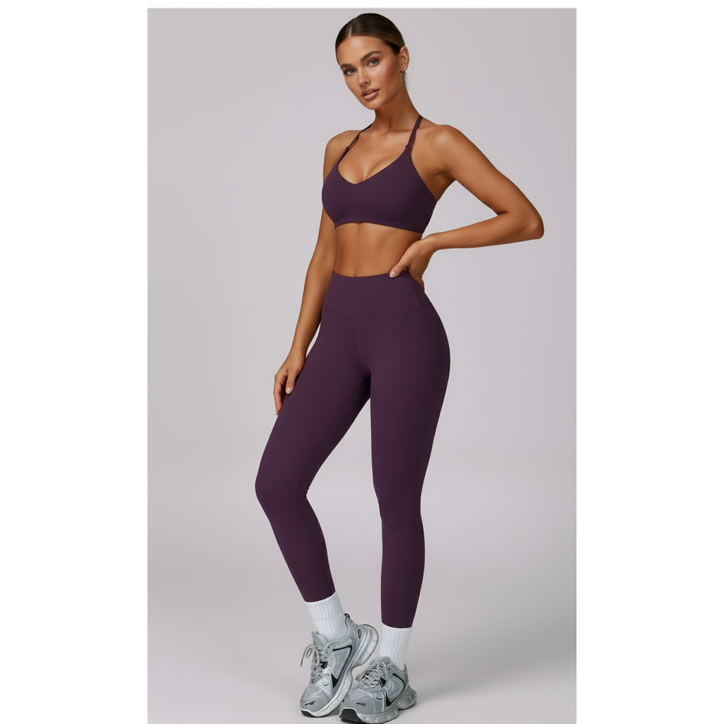 Woman wearing a purple sports bra and leggings set on a light gray background
