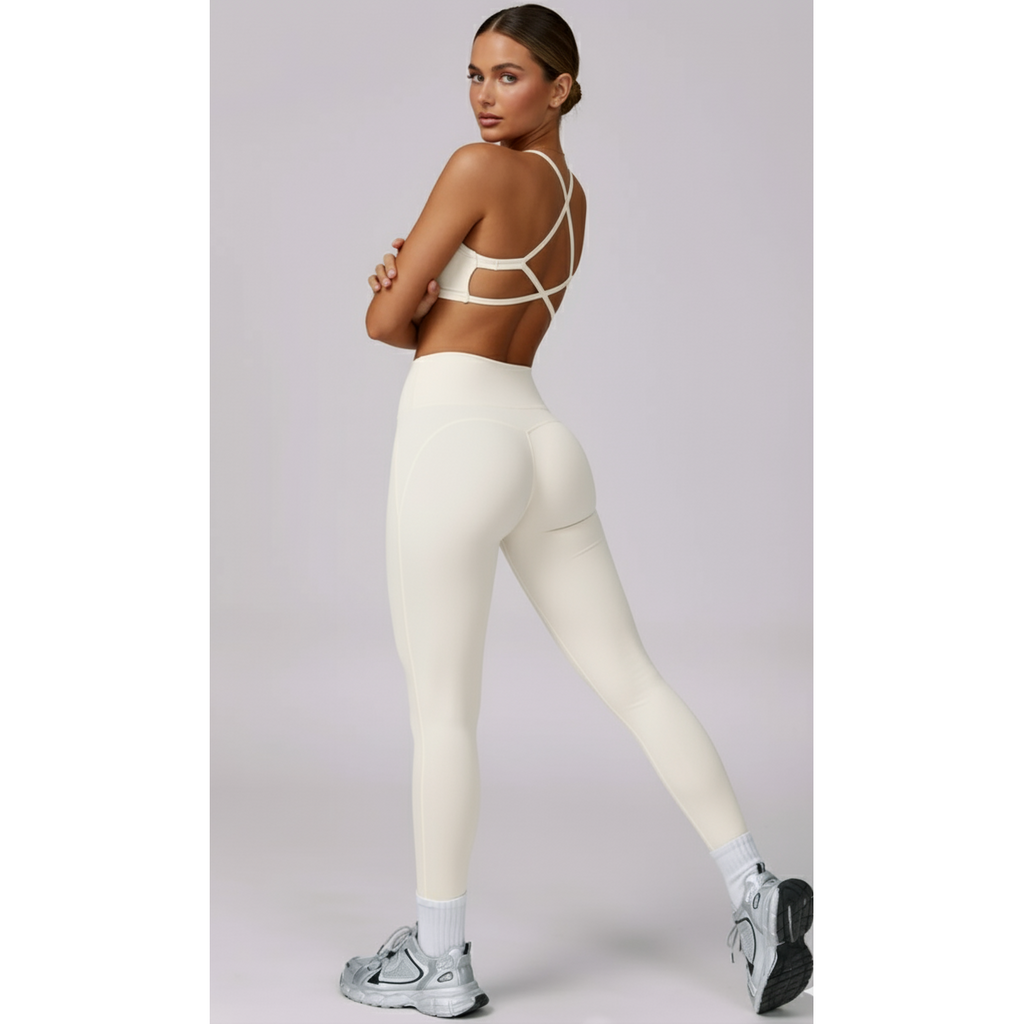 Woman wearing a white sports bra and leggings on a light gray background