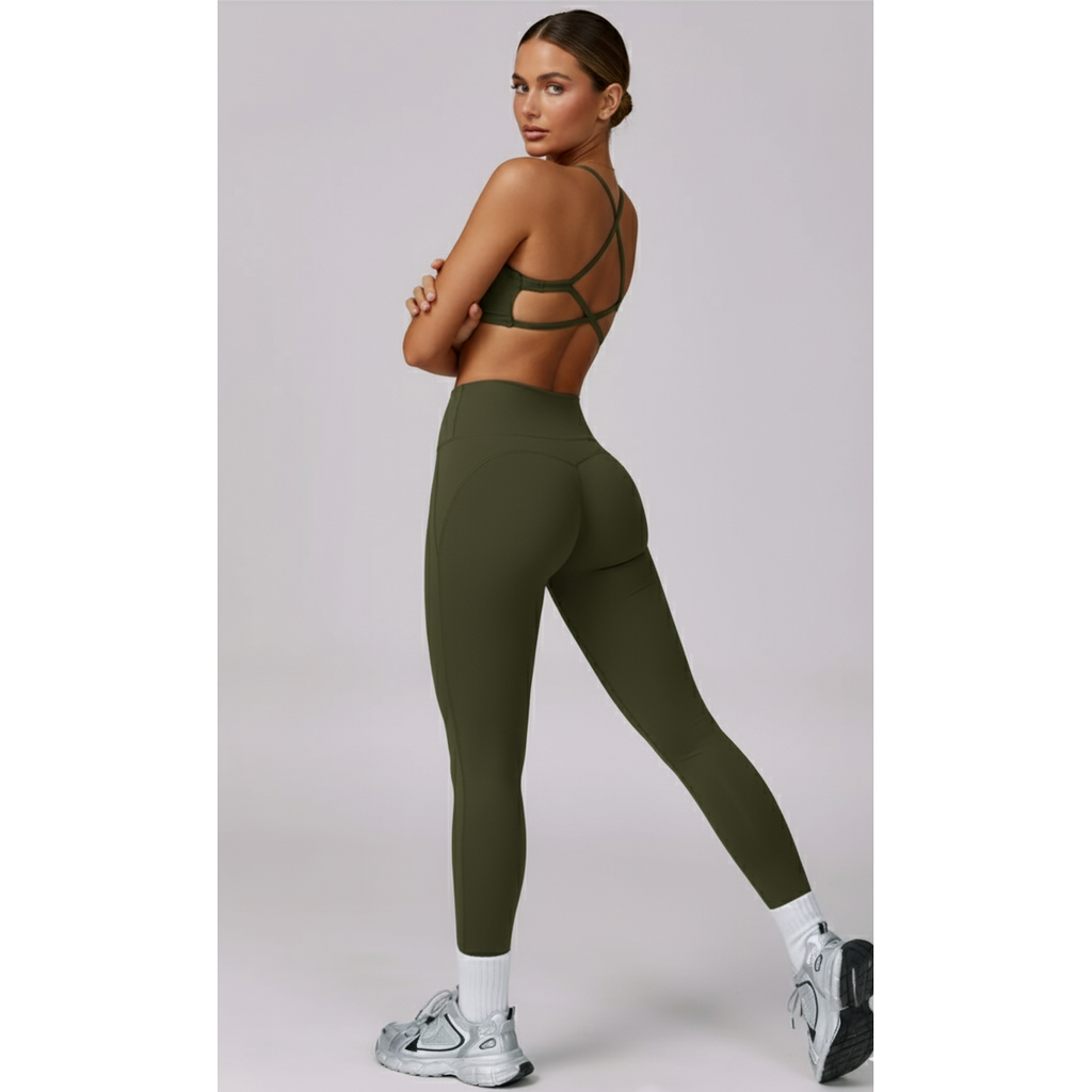 Woman wearing green athletic leggings and sports bra on a light gray background