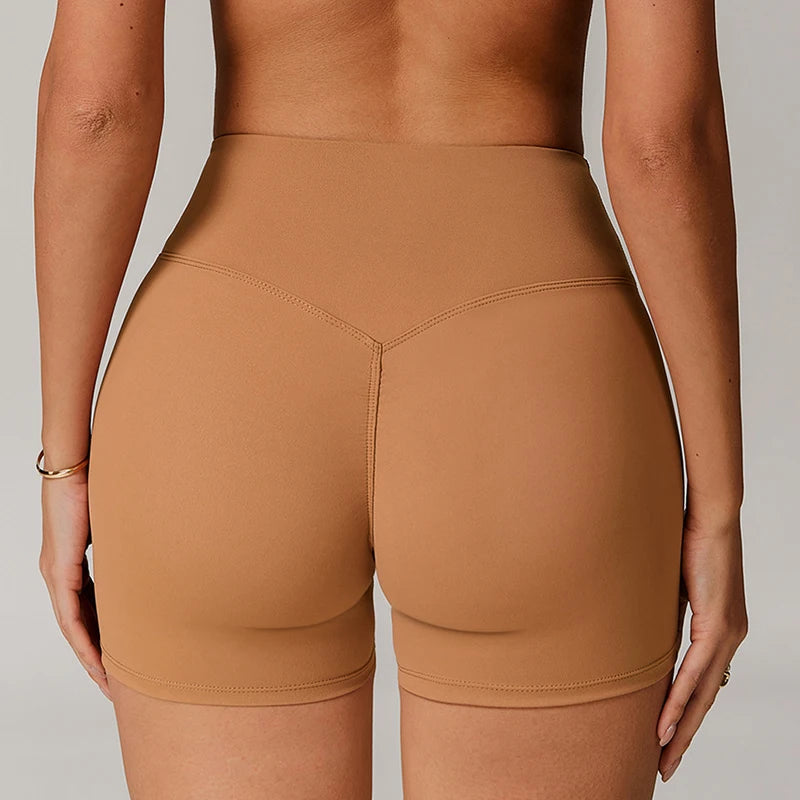 Xooie Fit women's active shorts in tan color shown from the back on a standing model
