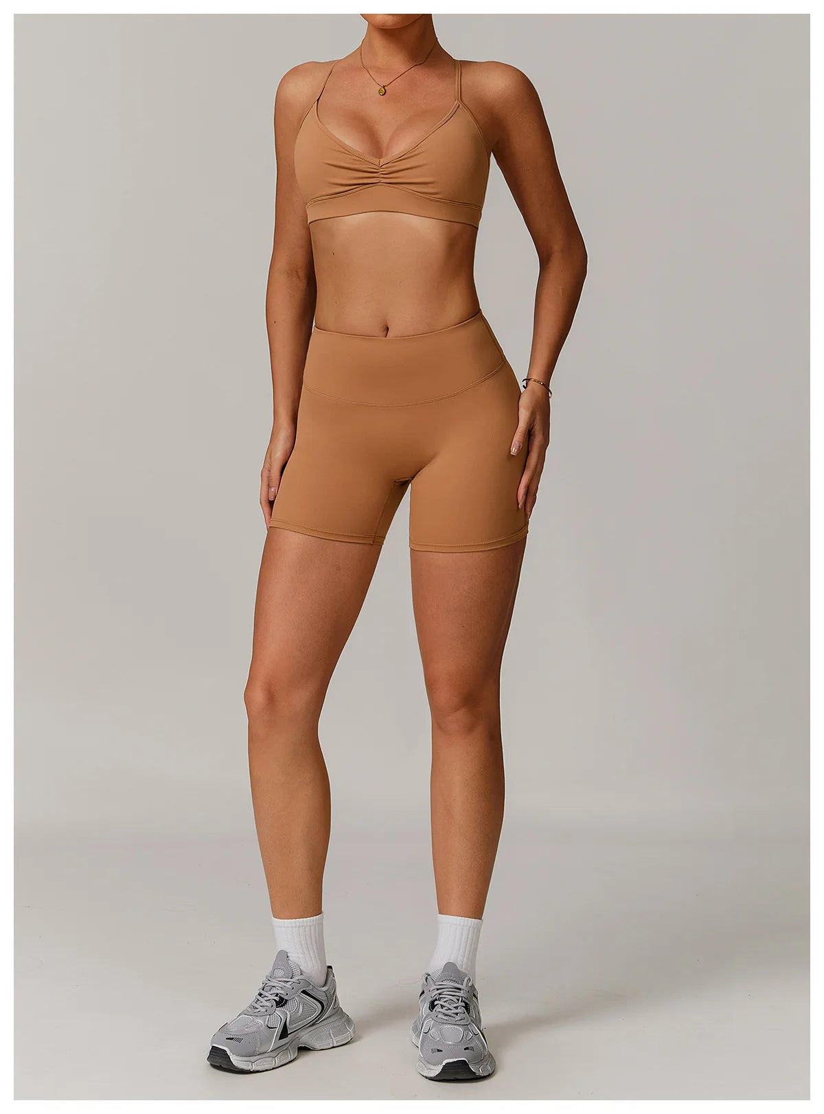 Xooie Fit women's active shorts in tan color paired with matching sports bra and gray sneakers