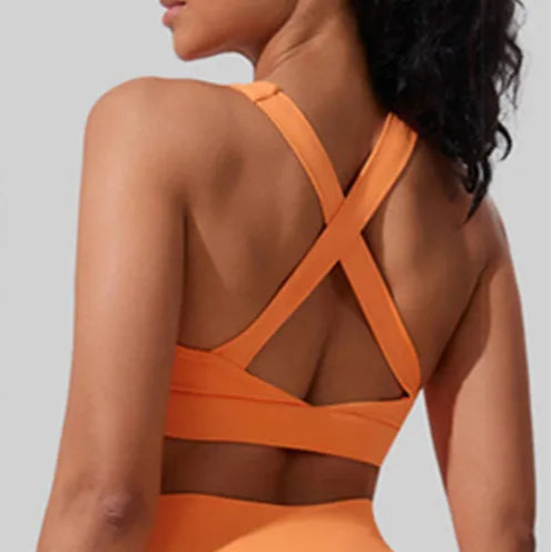 Back view of Xooie Fit women's active sports bra in vibrant orange with stylish cross straps