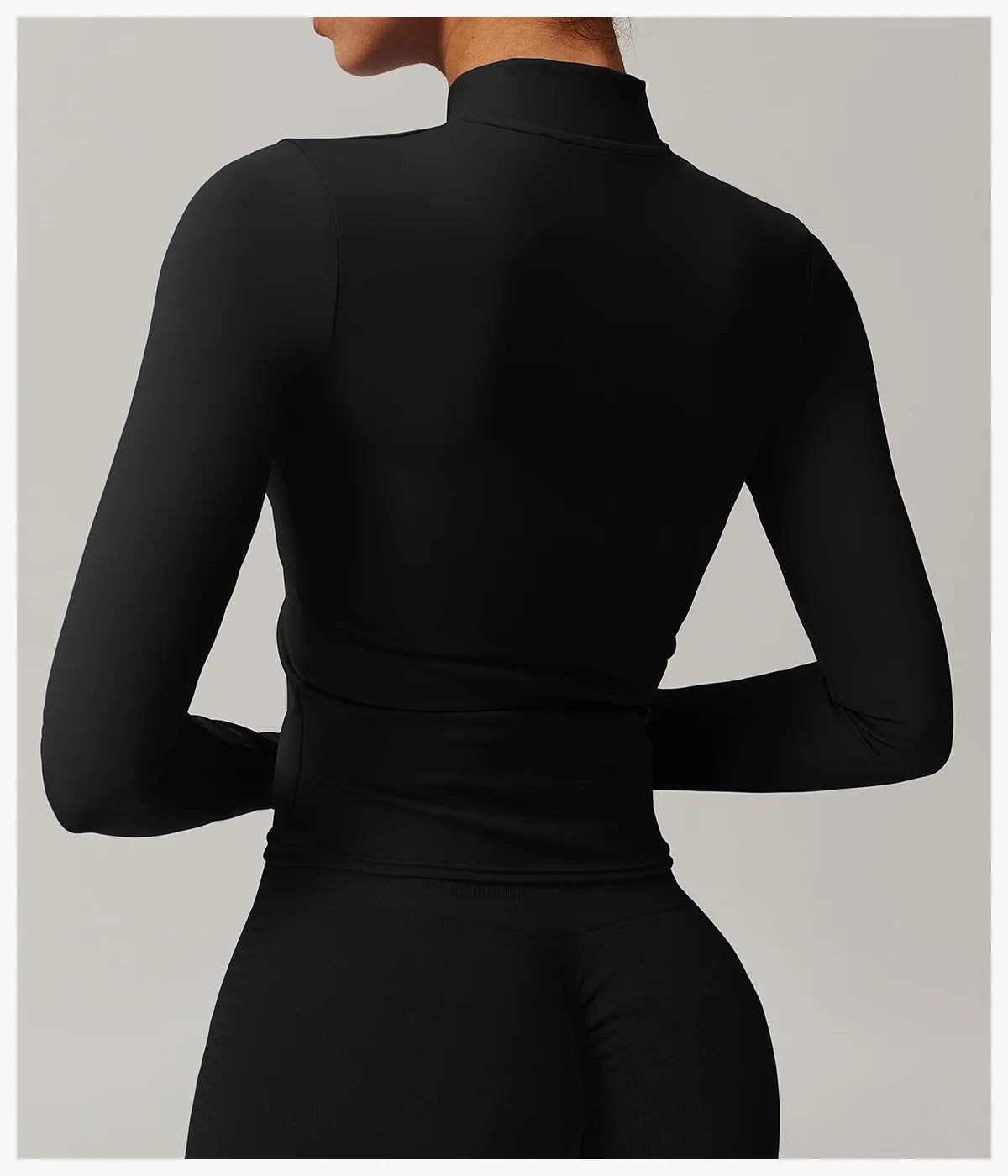 Back view of black women's fitness jacket with thumb holes by Xooie Fit featuring a sleek, fitted design