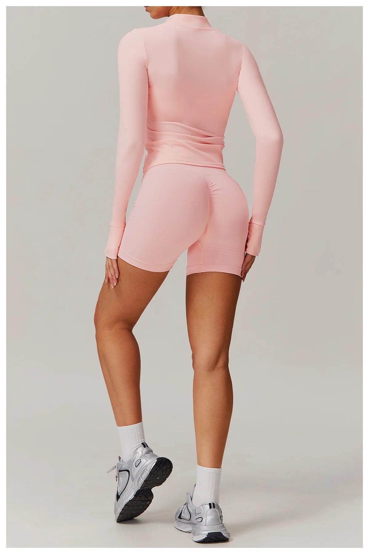 Xooie Fit women's fitness jacket with thumb holes in light pink worn with matching shorts