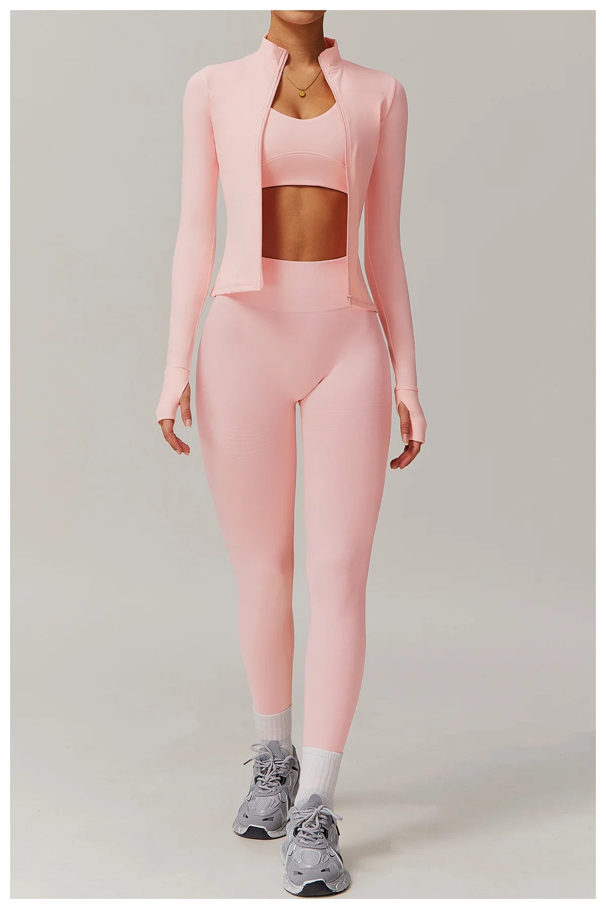 Xooie Fit women's fitness jacket with thumb holes in light pink worn with matching leggings and sports bra