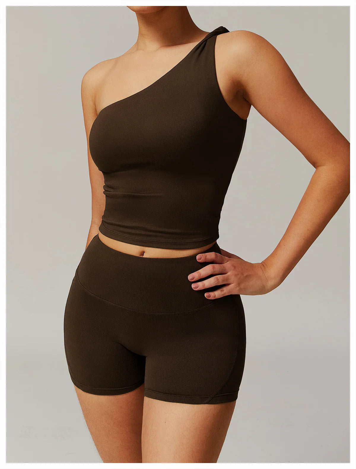 Xooie Fit women's fitness matching set with one-shoulder crop top and high-waisted shorts in dark brown