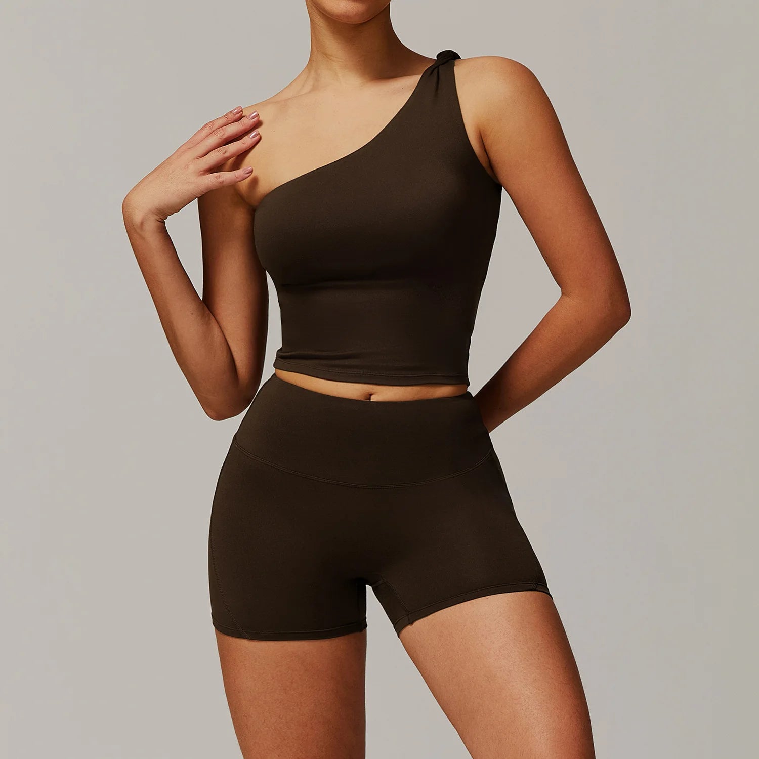Xooie Fit women's fitness matching set featuring a one-shoulder crop top and high-waisted shorts in dark brown