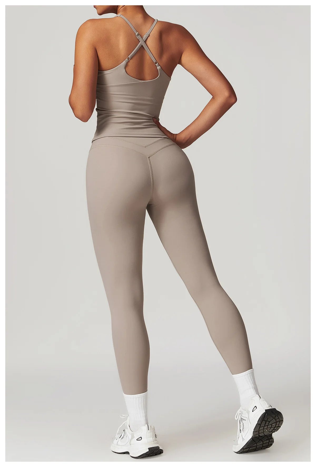 Back view of woman wearing women's fitted activewear set in beige with crisscross straps and leggings by Xooie Fit