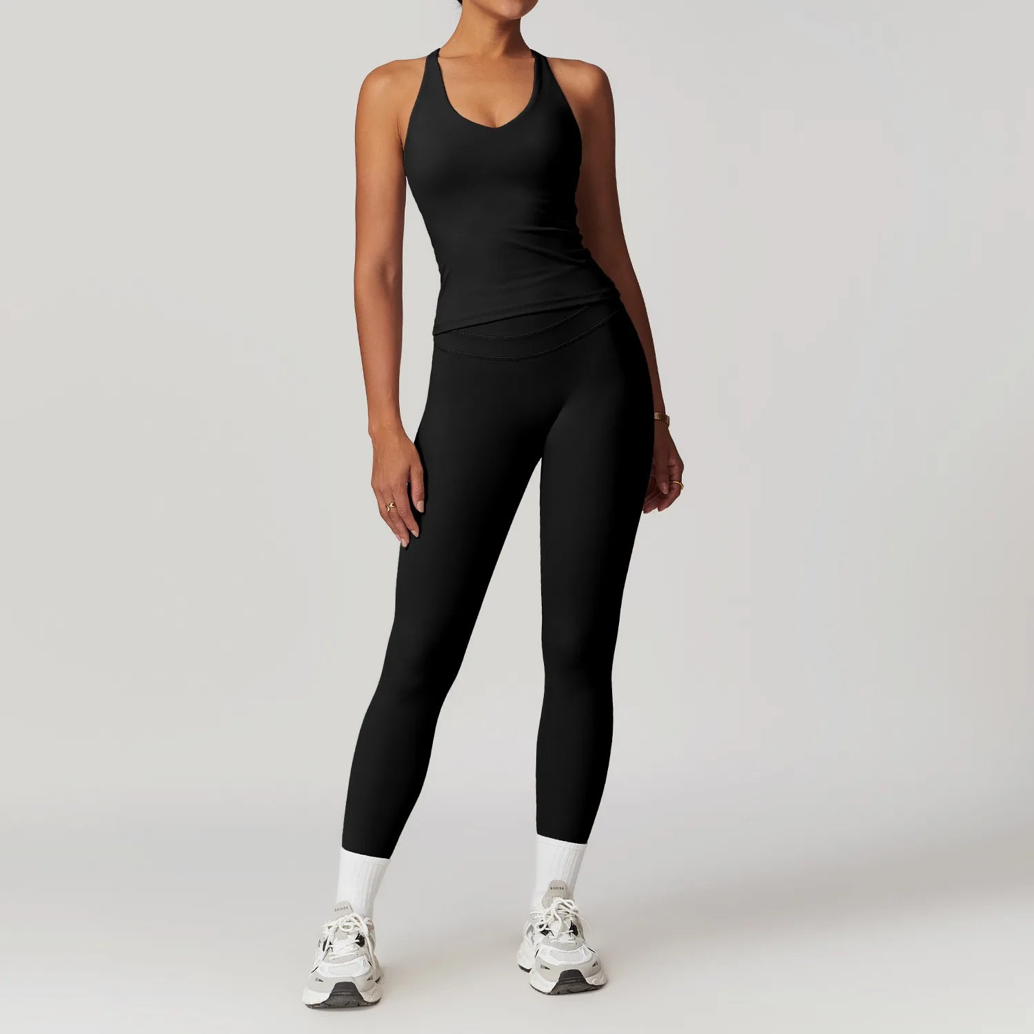 Model wearing Xooie Fit women's fitted activewear set in black with tank top and leggings