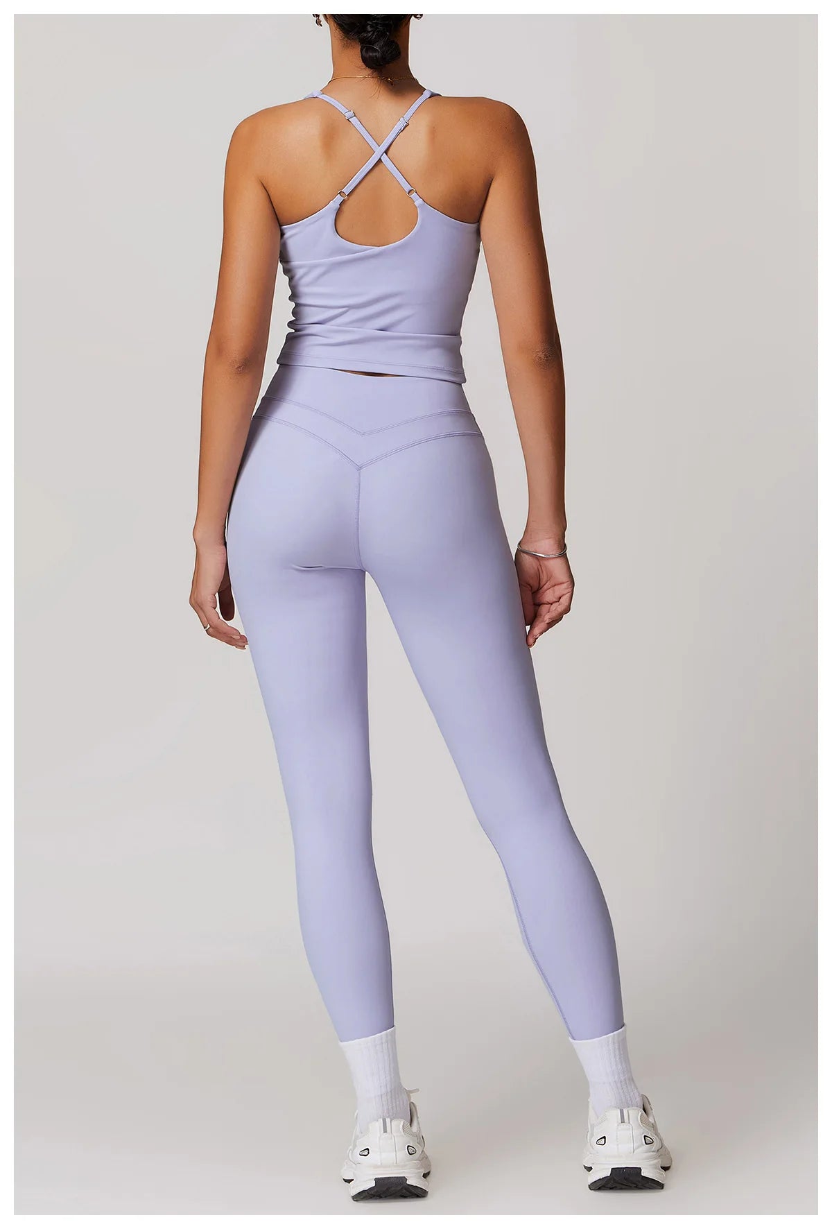 Back view of woman wearing lavender women's fitted activewear set by Xooie Fit with crisscross straps