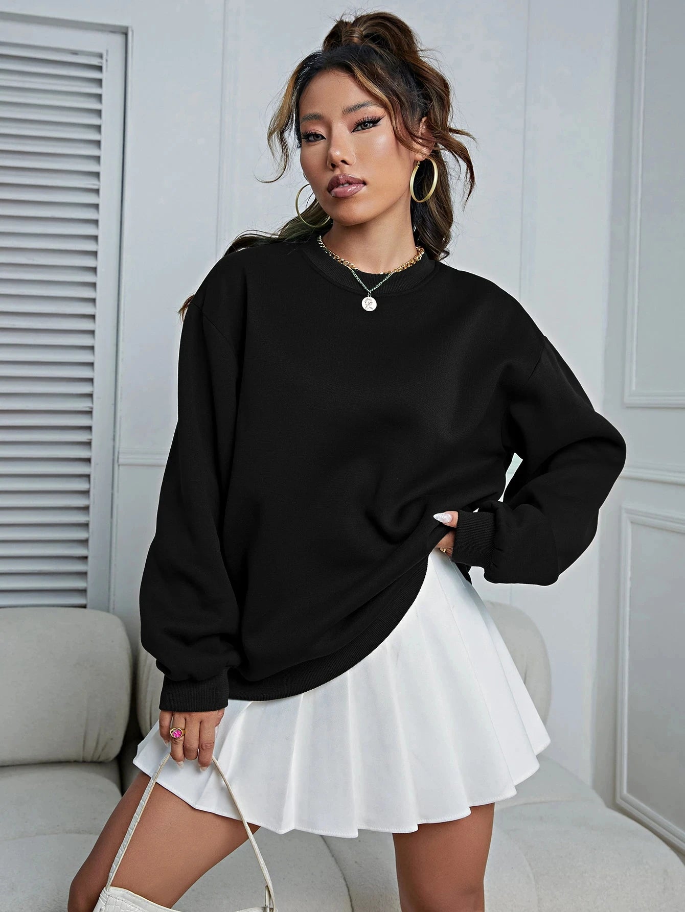 Stylish women's oversized sweatshirt in black, paired with a white skirt for a trendy look