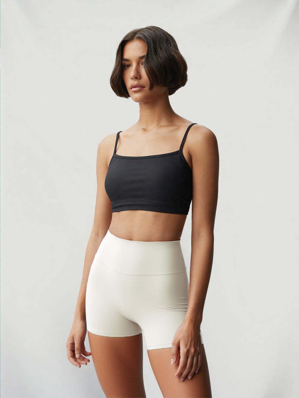 Model wearing Xooie Fit women's stretchy workout shorts in white with a black crop top