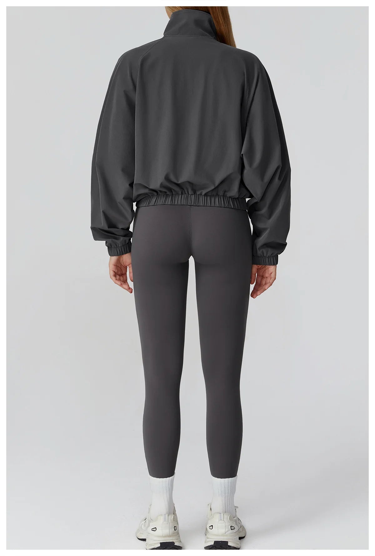 Back view of Xooie Fit women's windproof fitness jacket paired with gray leggings