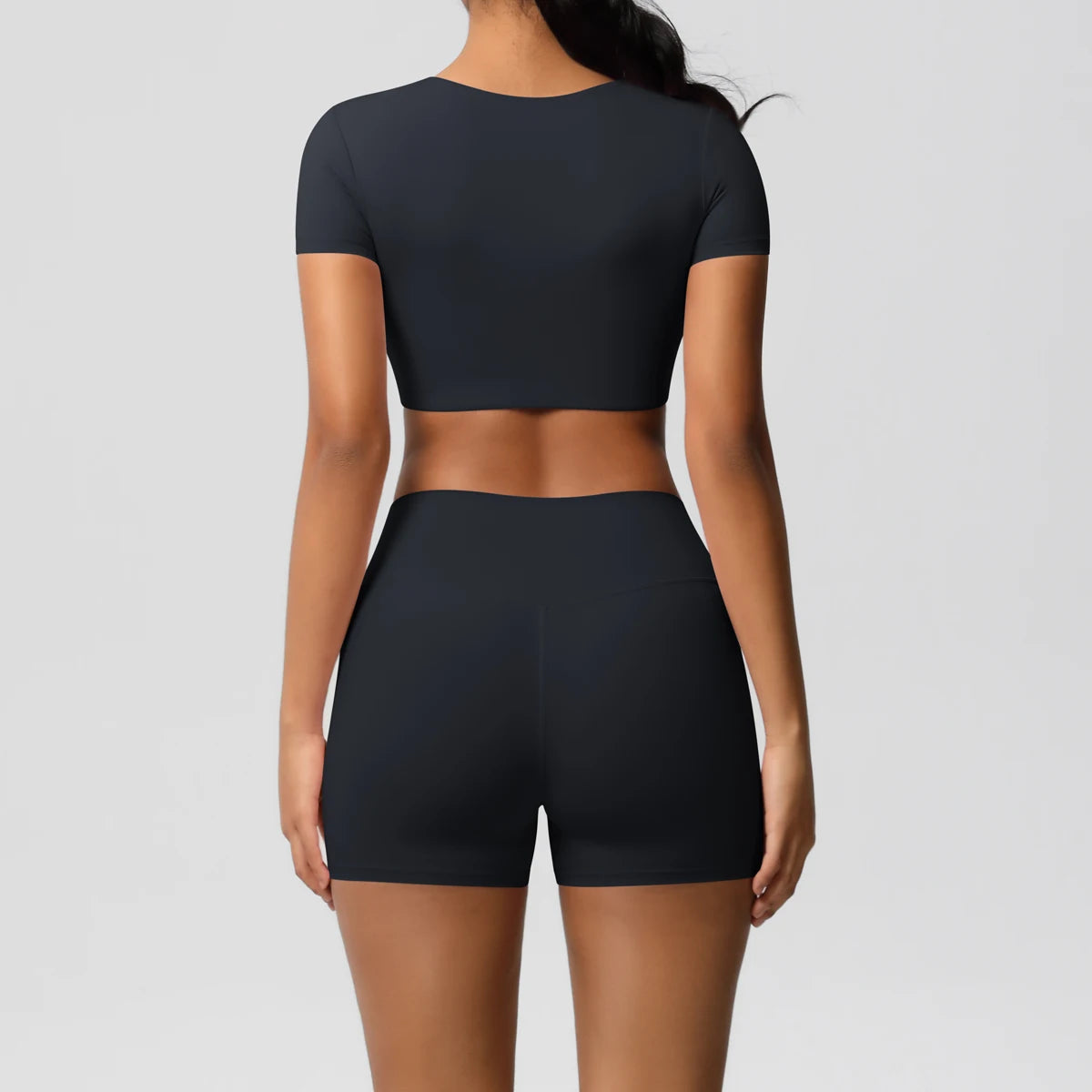 Back view of women's workout crop top and shorts set in black by Xooie Fit with short sleeves and high waist shorts