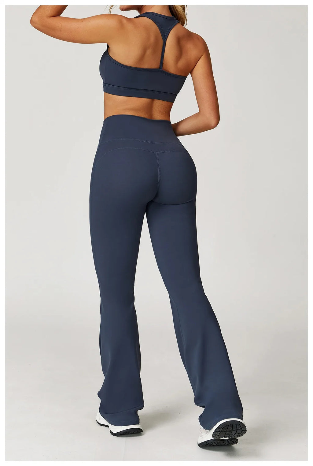 Xooie Fit women's workout set flared pants in dark blue modeled from the back with a matching sports bra