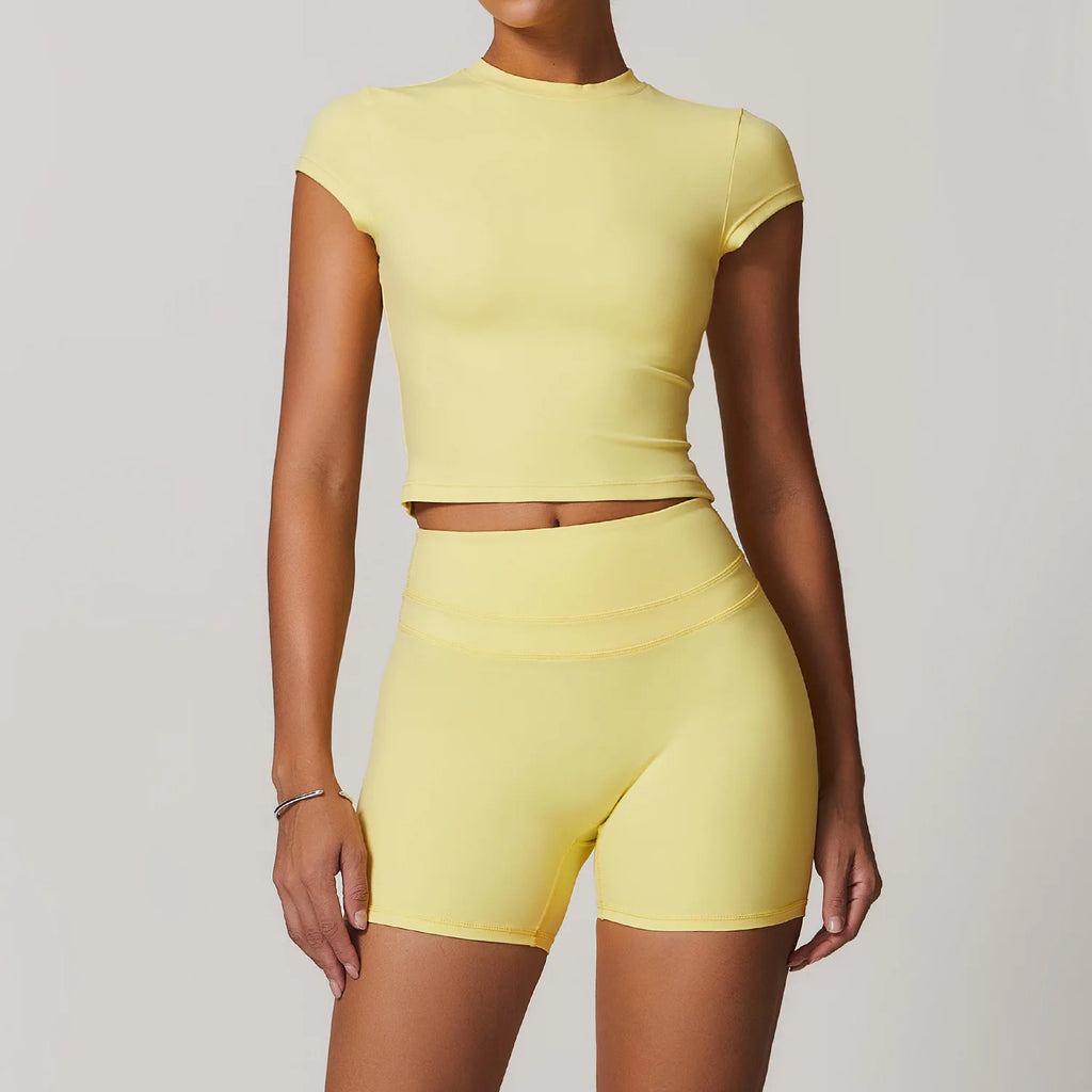 Xooie Fit womens workout set in light yellow featuring a short sleeve cropped top and high waist shorts