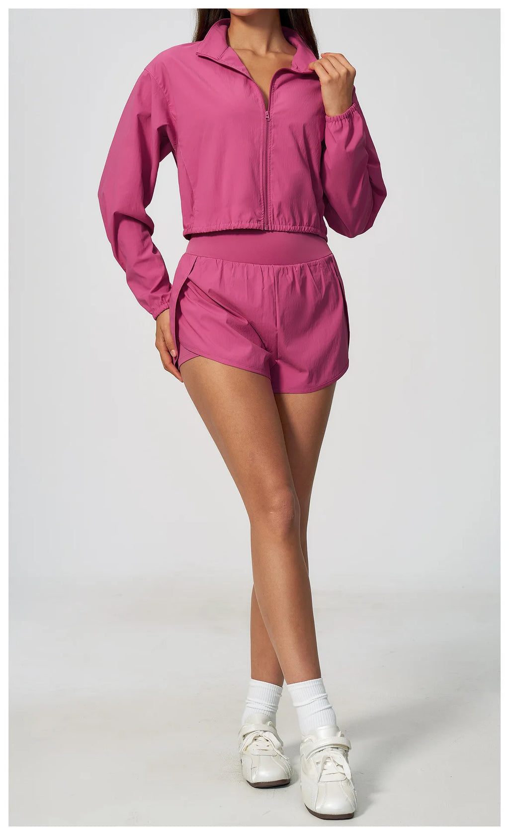 Pink zip-up athletic jacket with long sleeves and matching drawstring shorts, side view